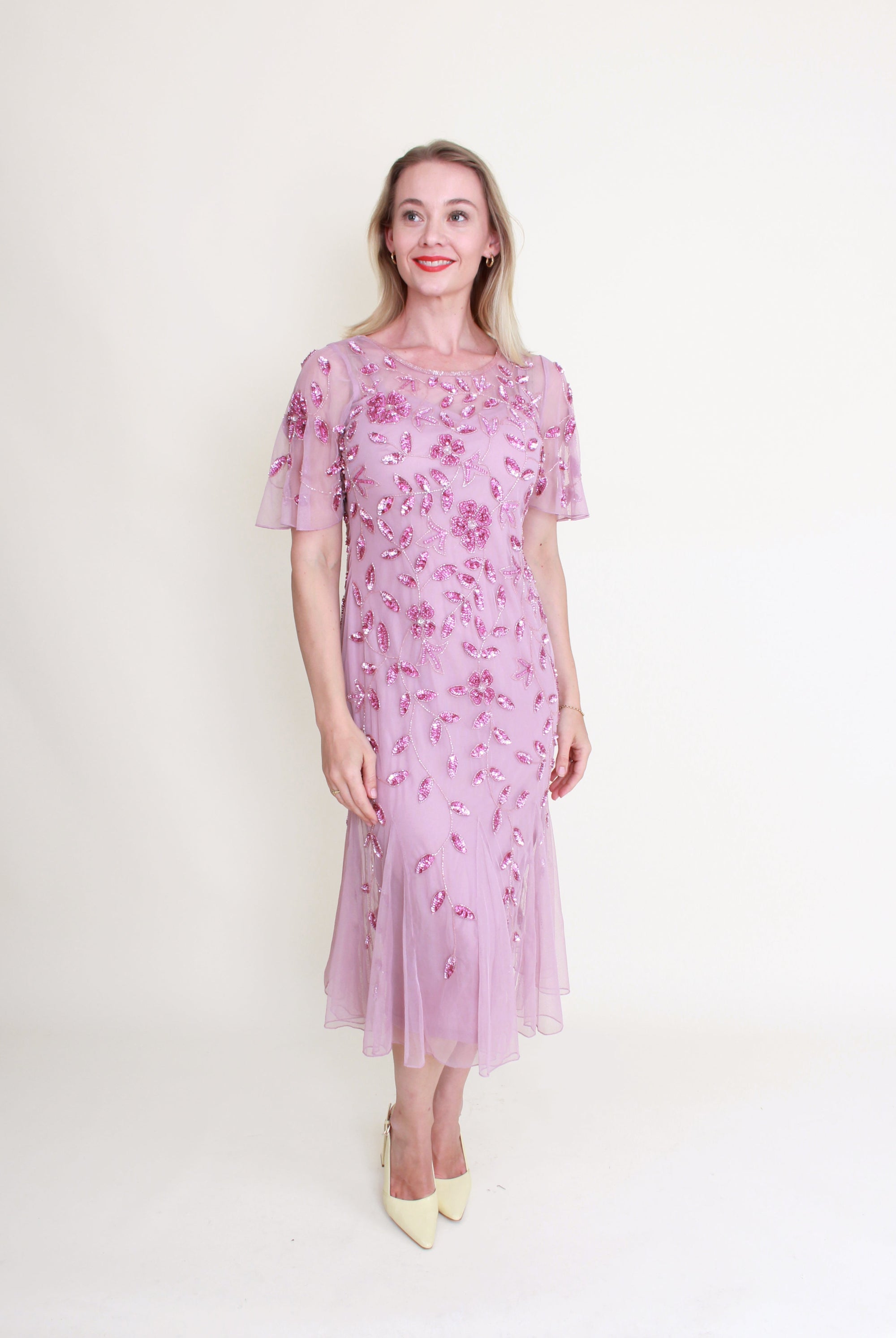 Woman wearing a pink floral dress against a white background