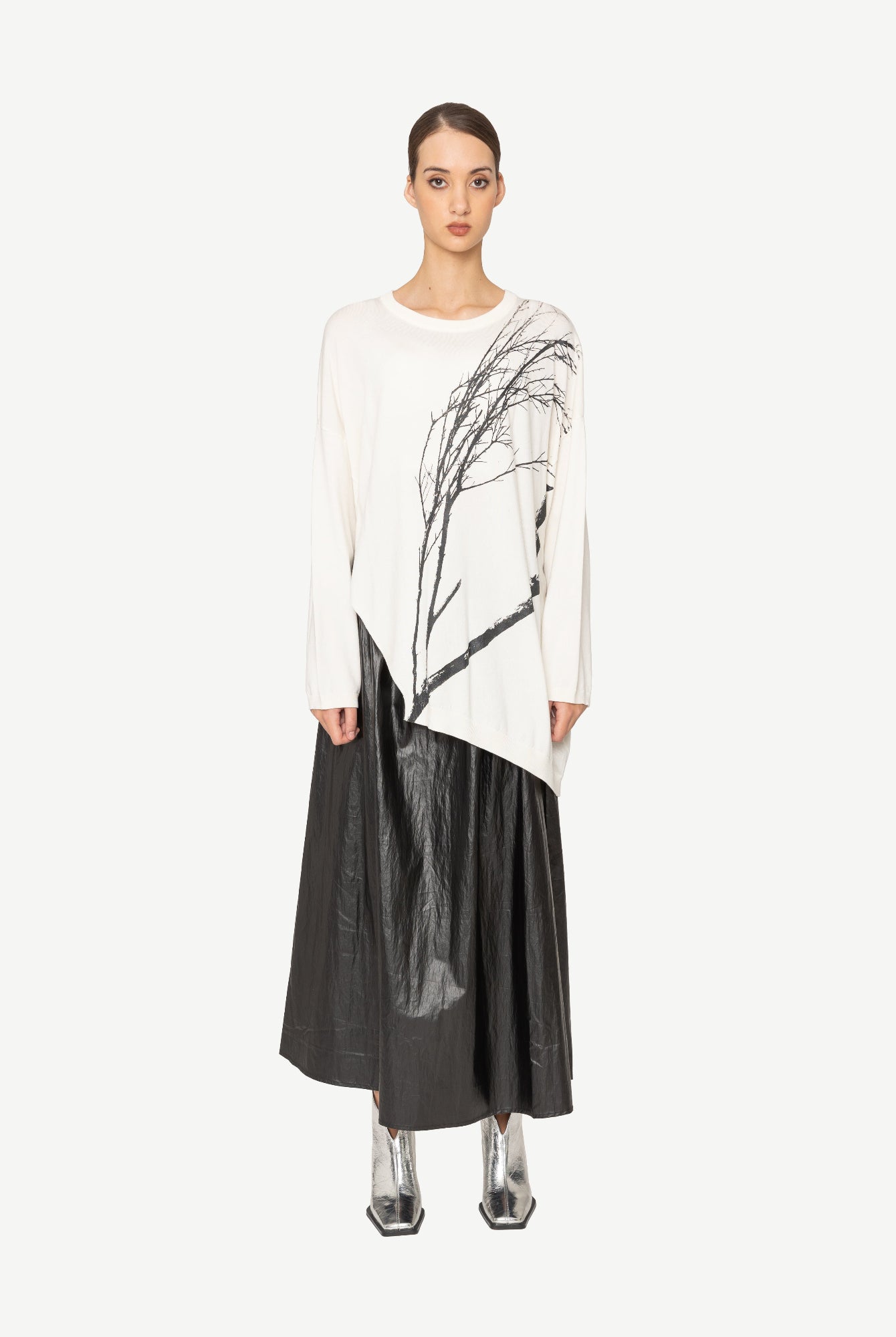 Woman wearing a white top with branch print and a long black skirt on a white background