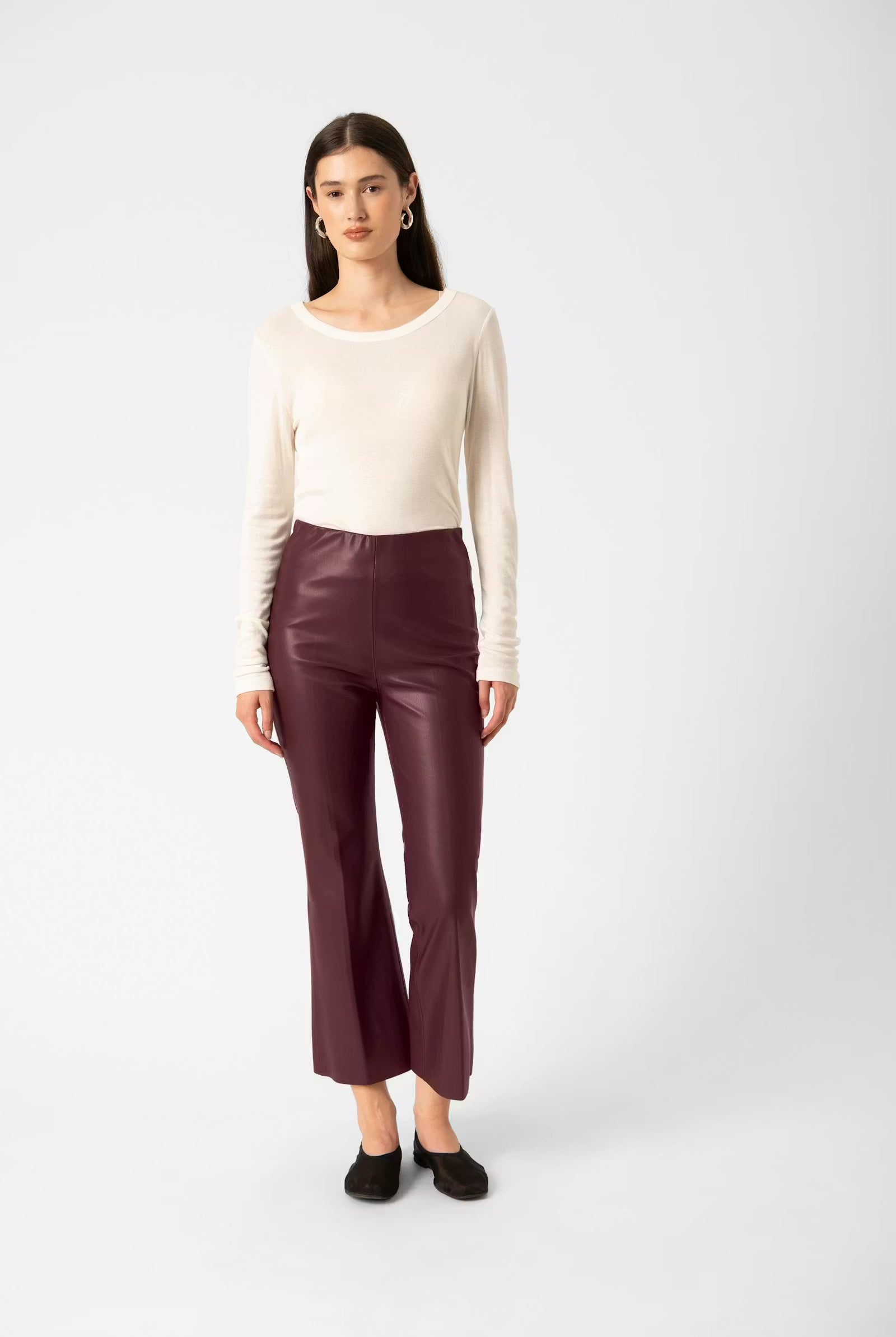Woman wearing a white top and maroon pants on a white background