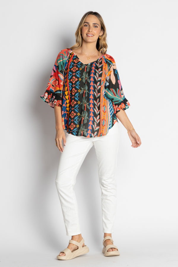 model wearing multi geometrical and floral print blouse and white jeans