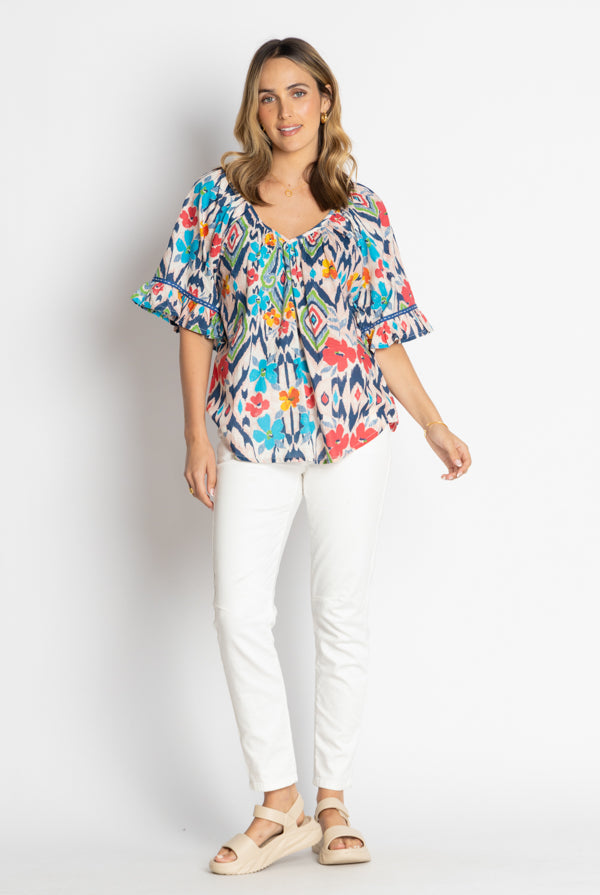 multi print gathered blouse and white jeans worn by model