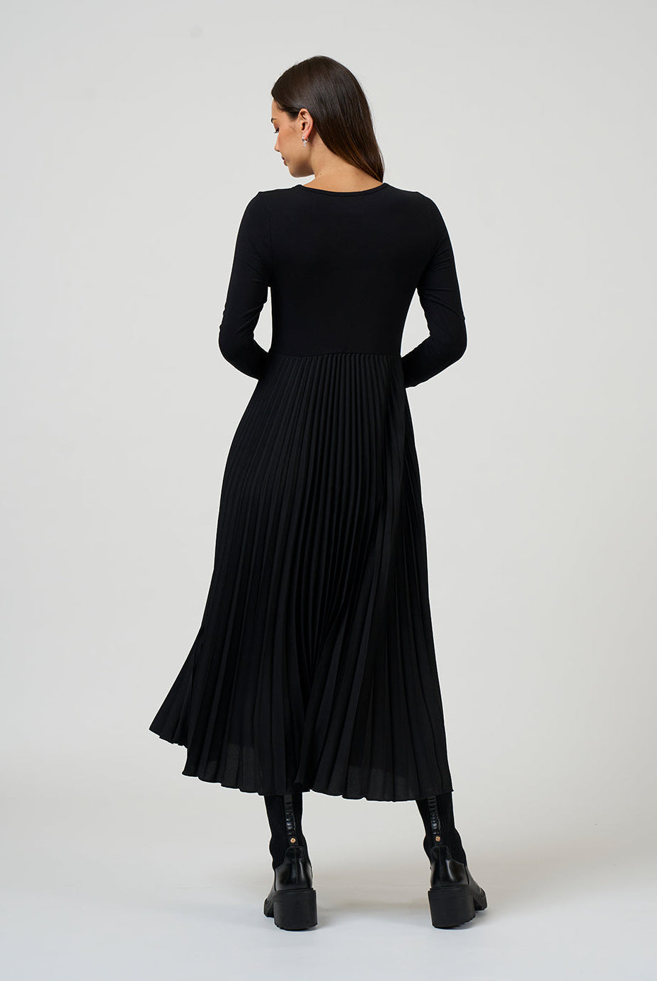 Woman wearing a black pleated dress on a white background