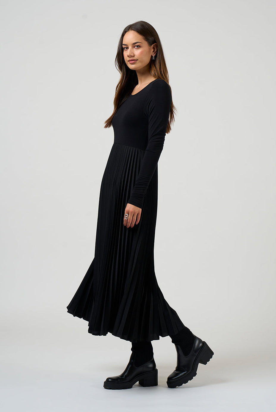Woman wearing a black dress standing against a white background
