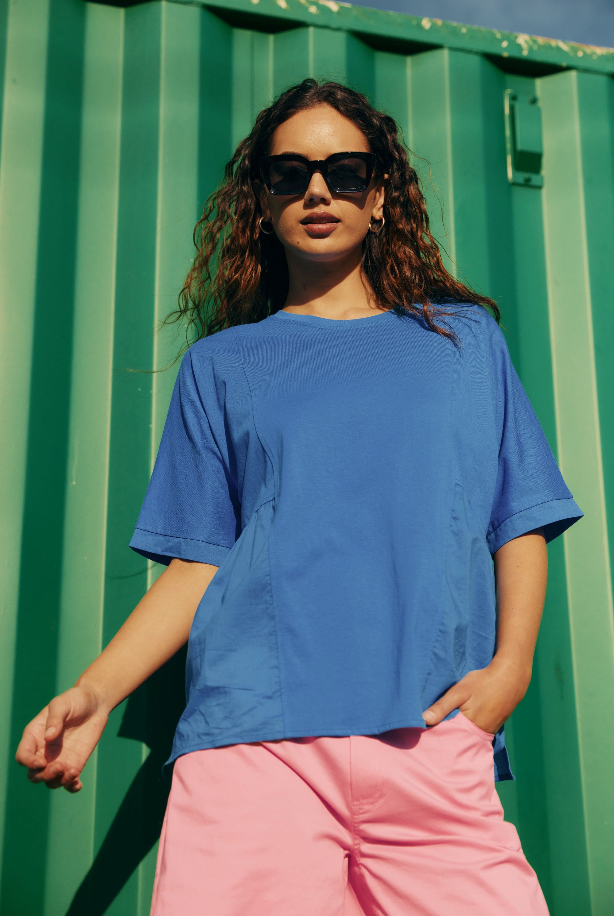 blue shirt with pink pant worn by model against green outddor background