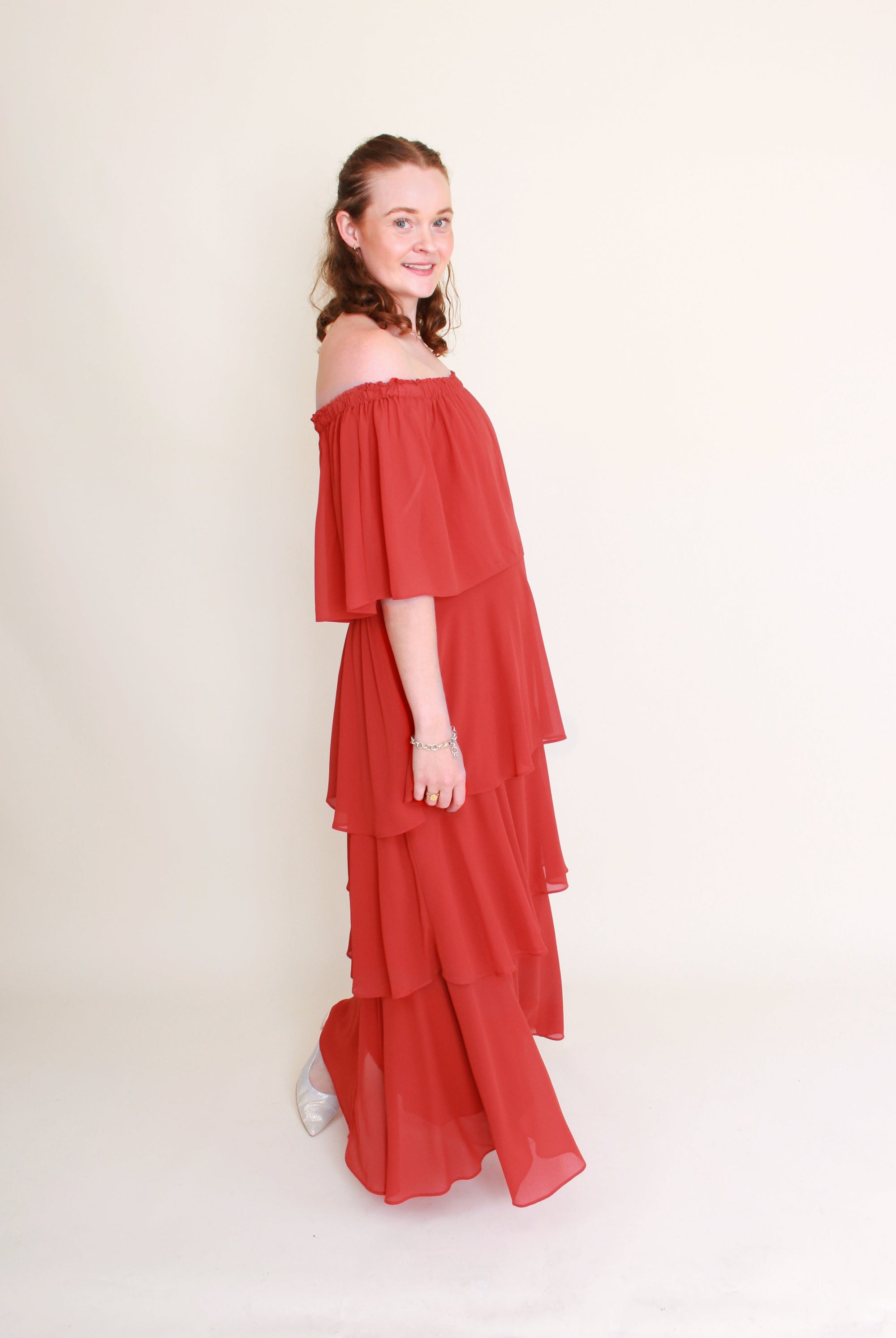 Woman wearing a red off-shoulder dress against a plain background