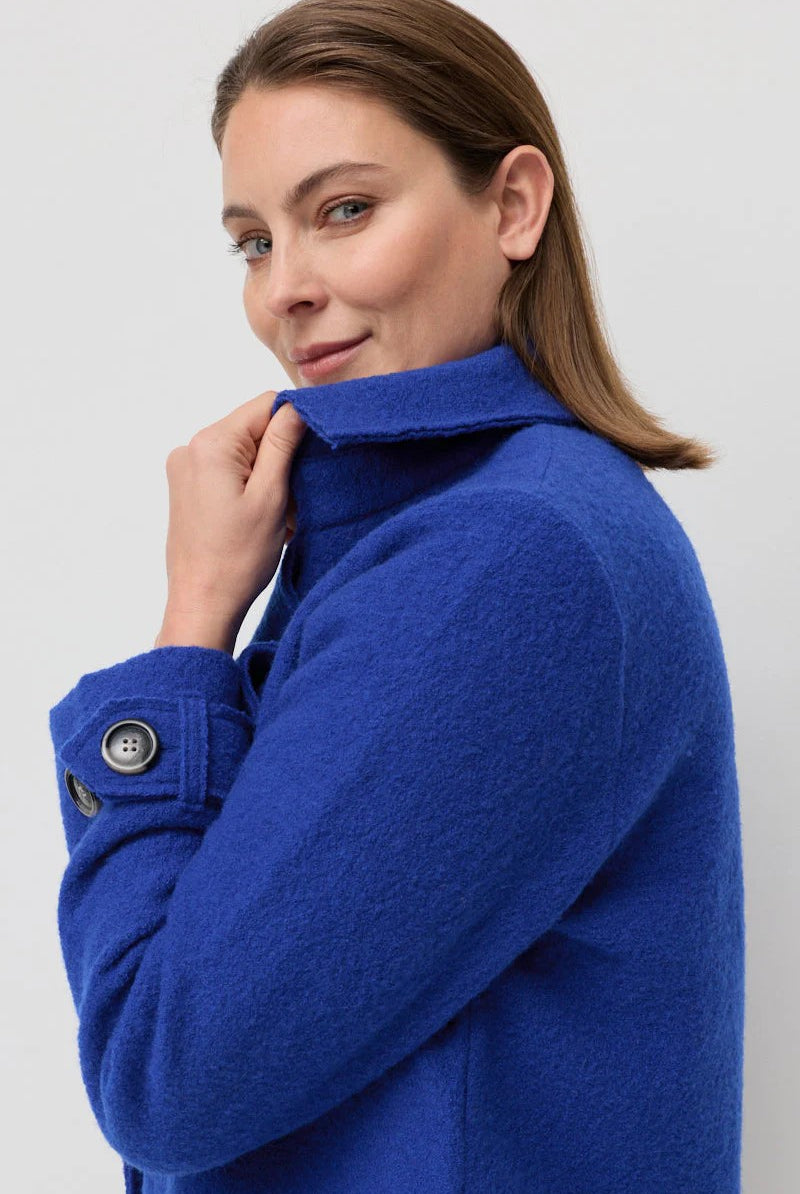 Woman wearing a blue coat against a plain background