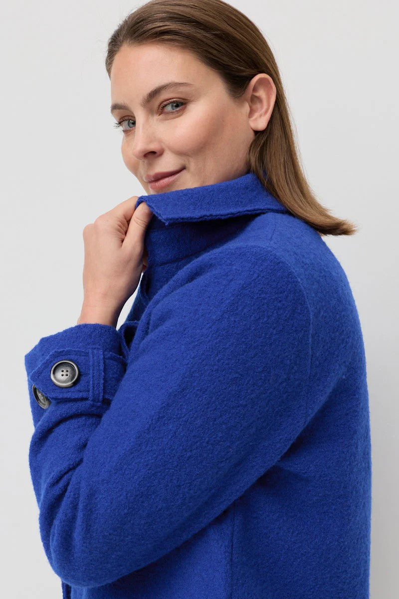 Woman wearing a blue coat against a plain background