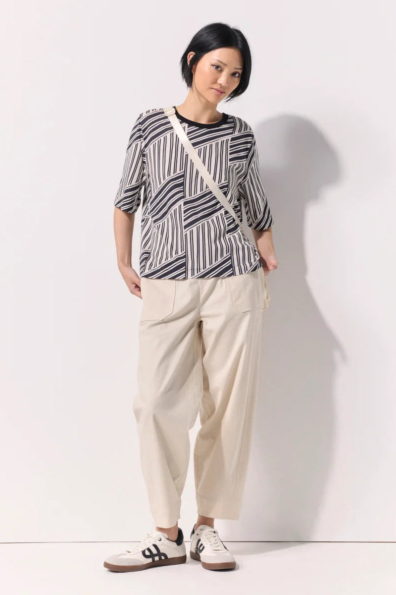 A woman wearing an abstract design black and white tee shirt against a white background.