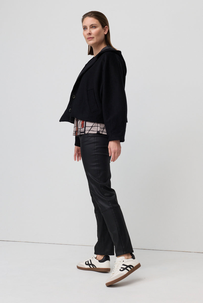 Woman wearing a black jacket and black pants on a white background