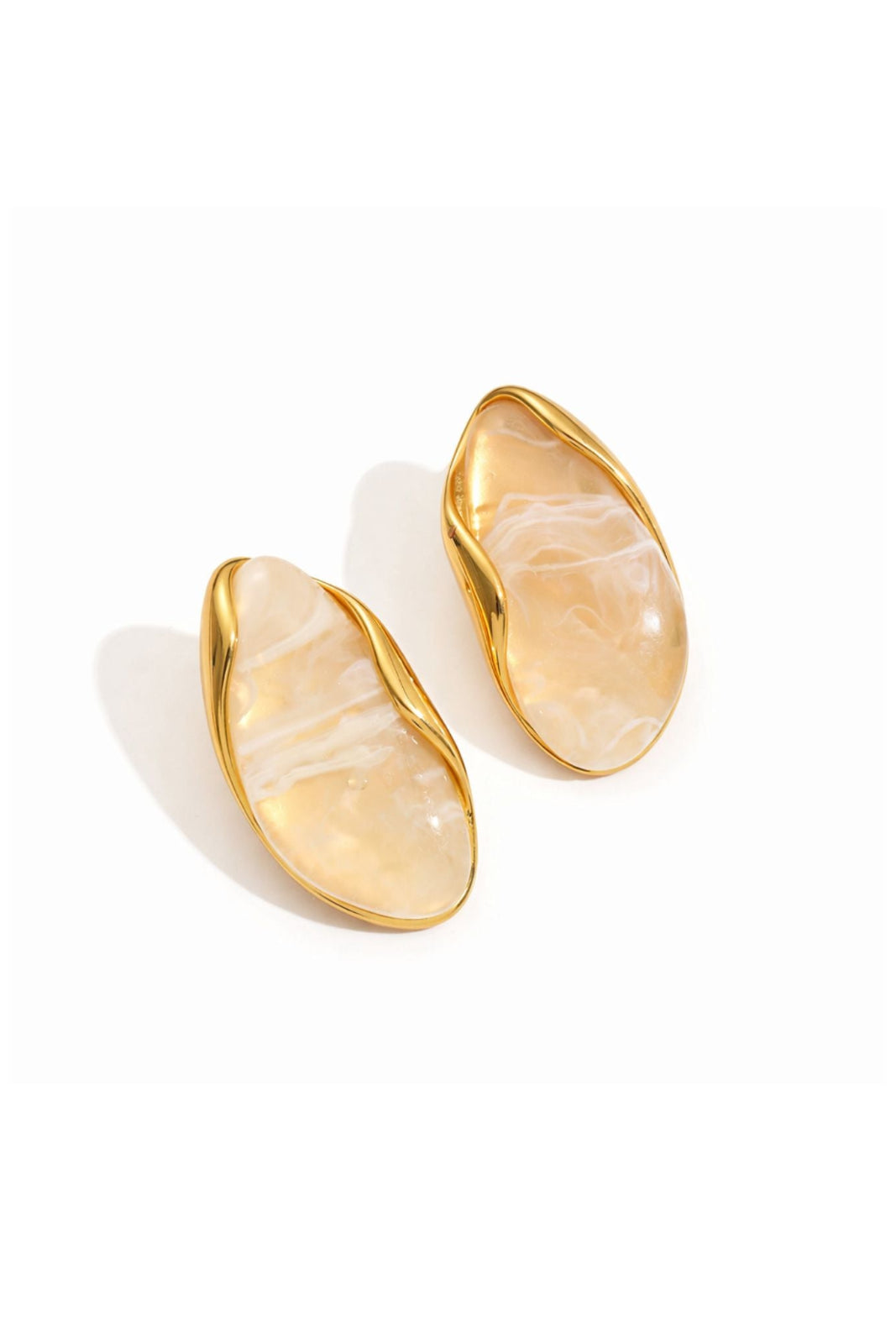 A pair of gold-toned oval stud earrings with smooth, organic-shaped cream and white marbled inlay, shown on a clean white background.