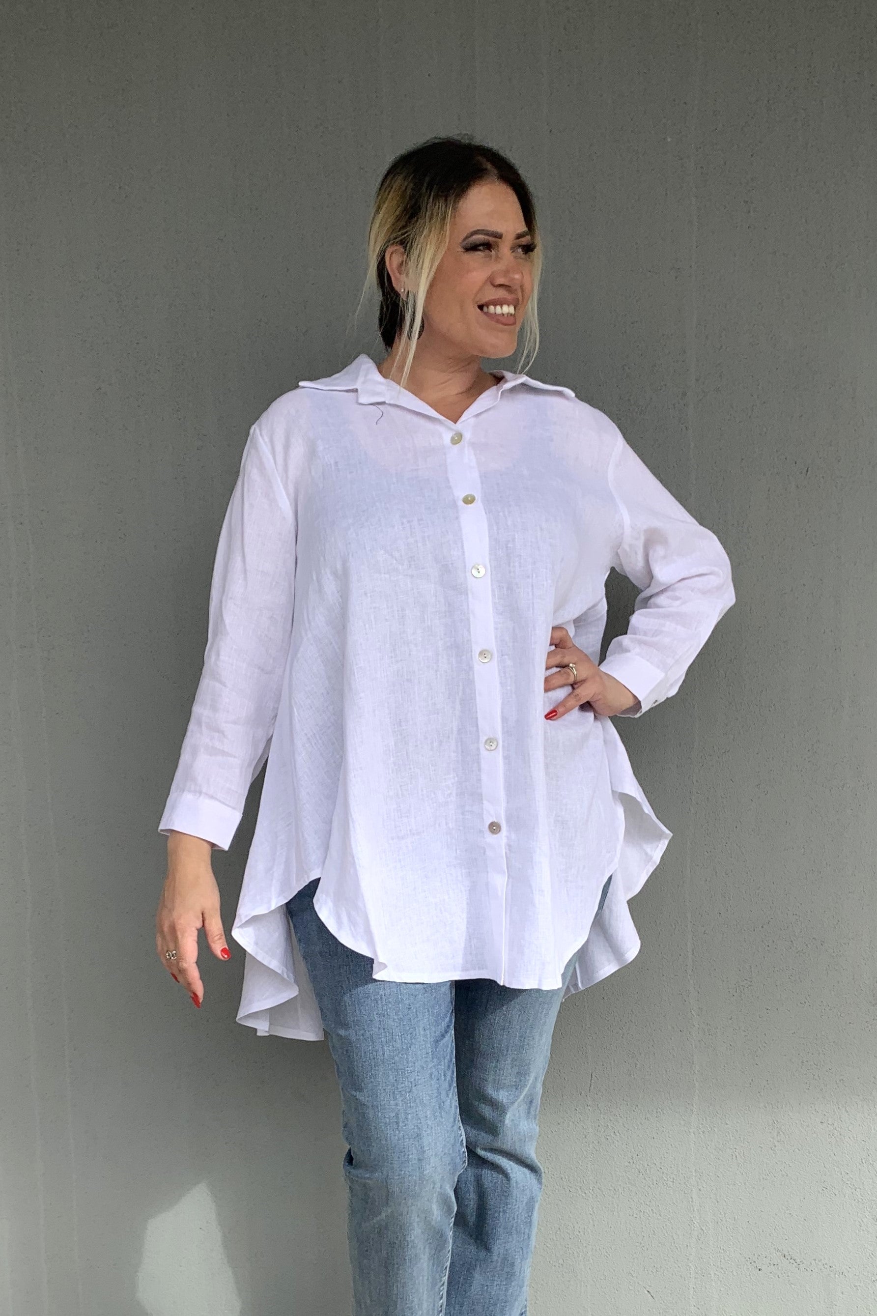 Woman wearing a white shirt and blue jeans against a gray background