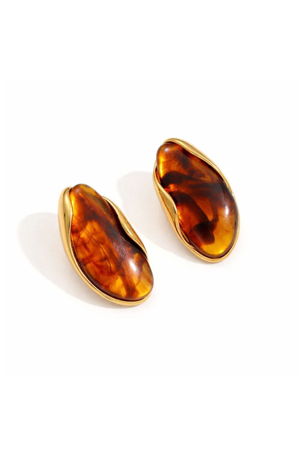 A pair of gold-toned stud earrings with organic, teardrop-shaped amber or tortoiseshell inlays, shown on a clean white background.