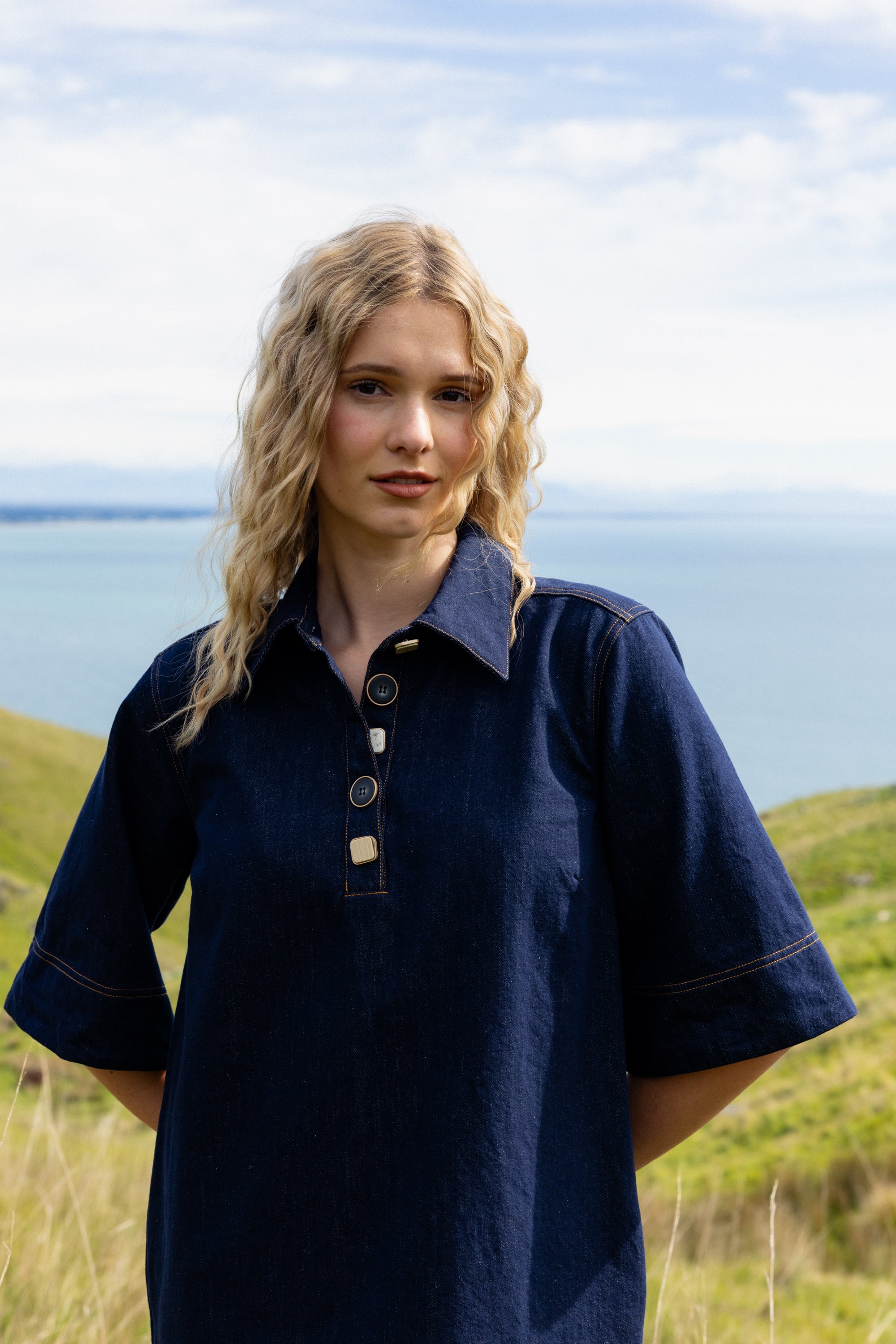 Woman wearing a navy blue dress with a collar in a scenic outdoor setting.