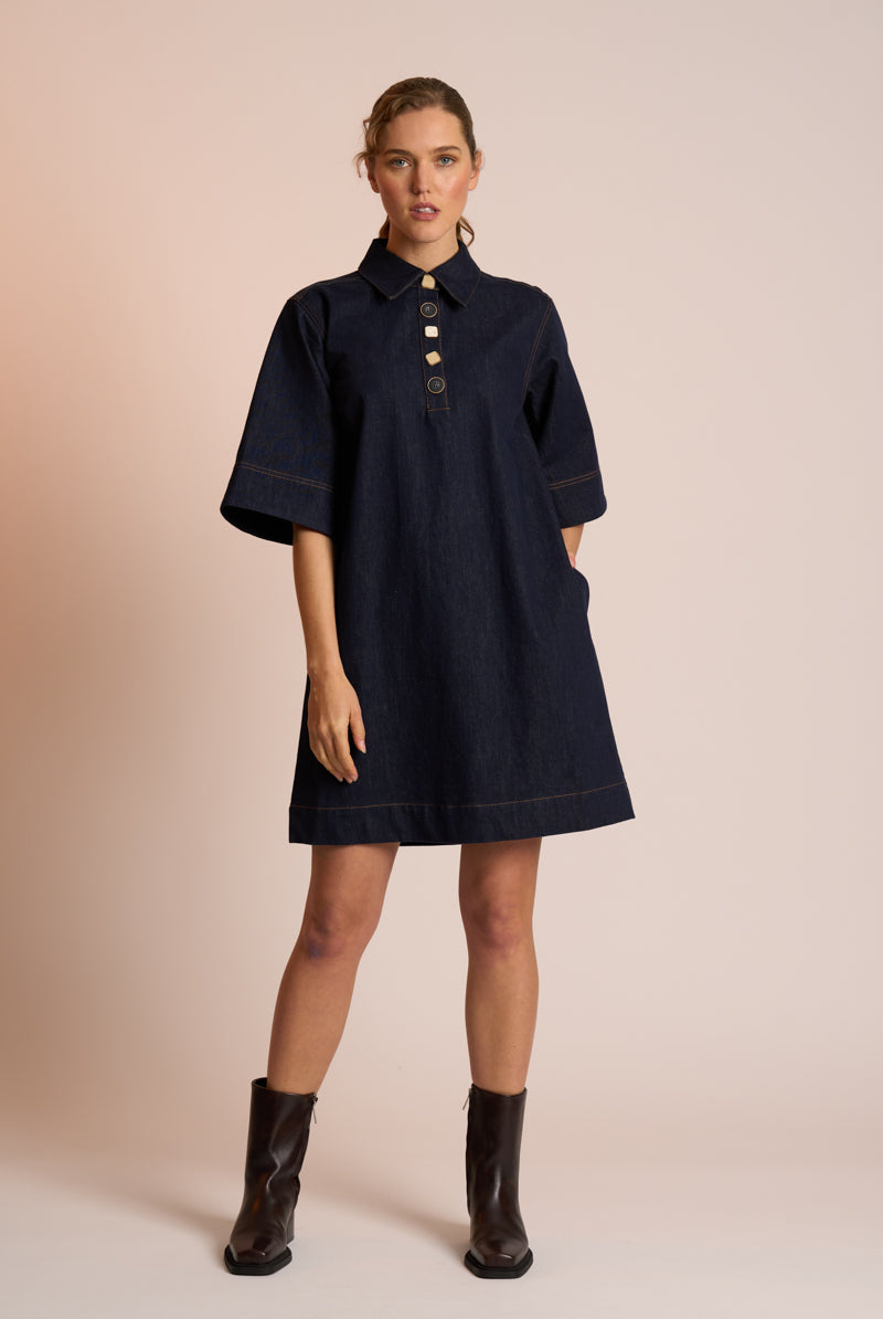 Woman wearing a navy dress with a beige background