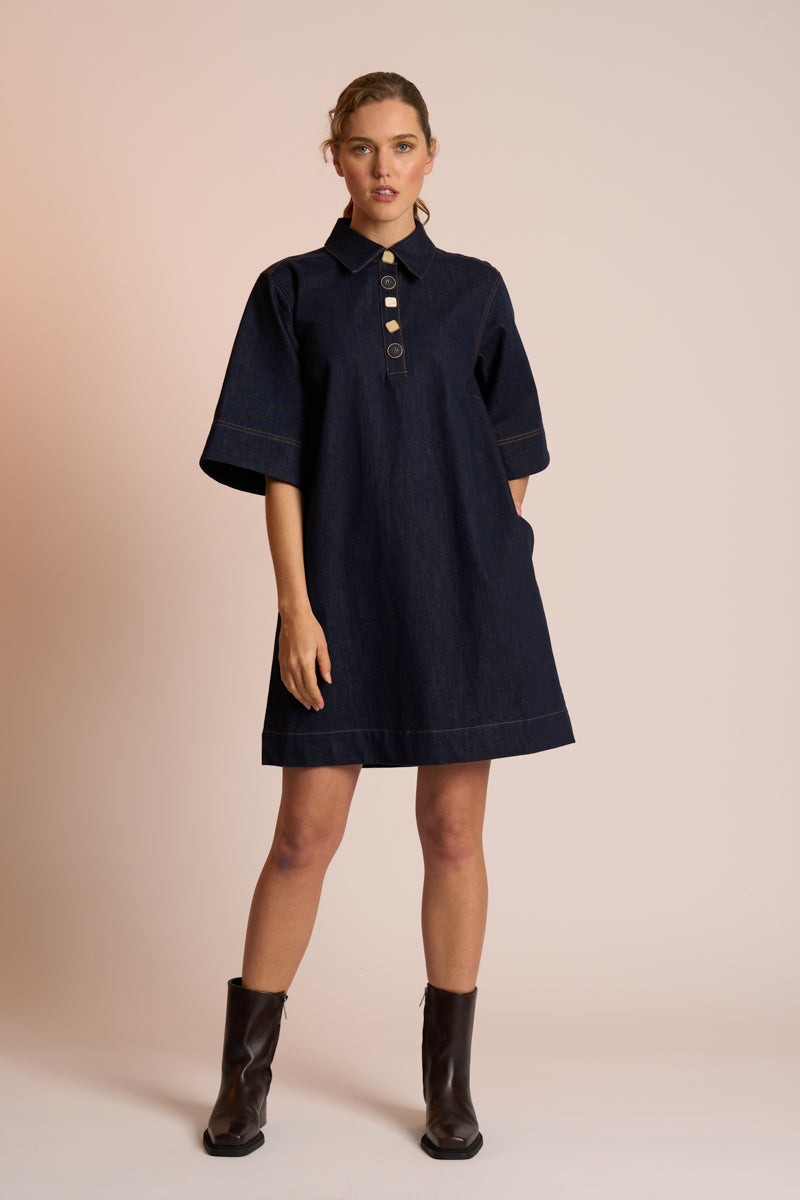 Woman wearing a navy dress with a beige background