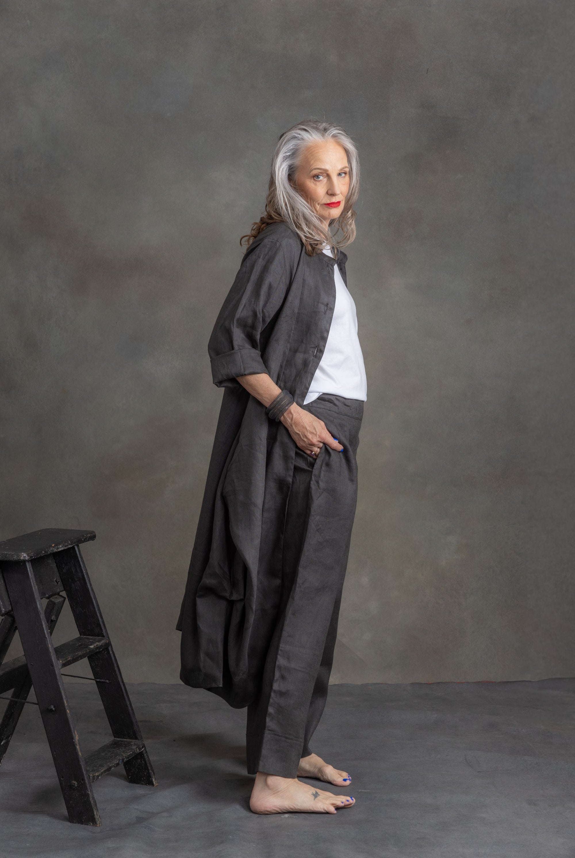 model wearing charcoal linen longline coat and matching pants in front of grey background