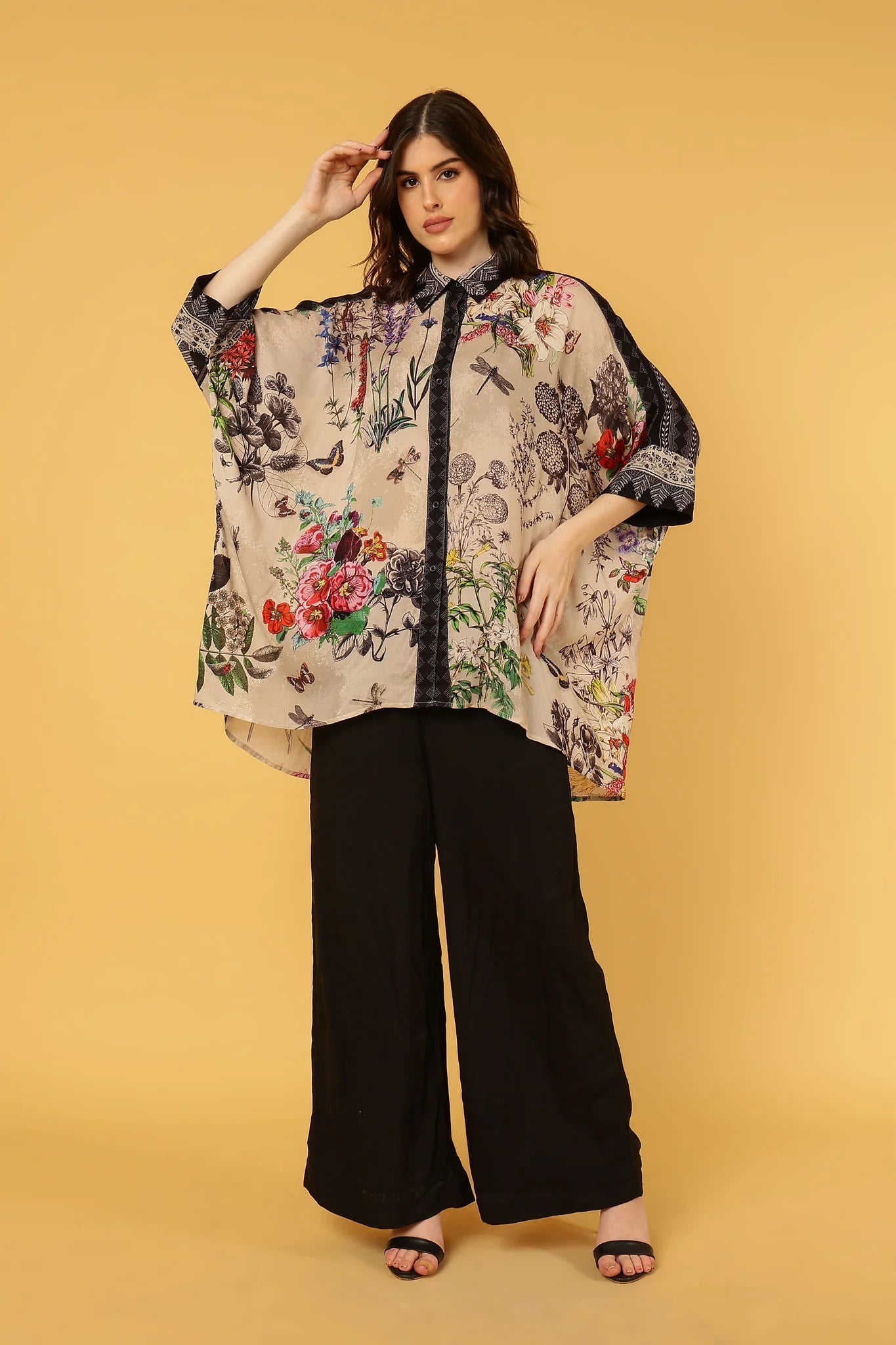 Woman wearing a floral blouse and black pants on a yellow background