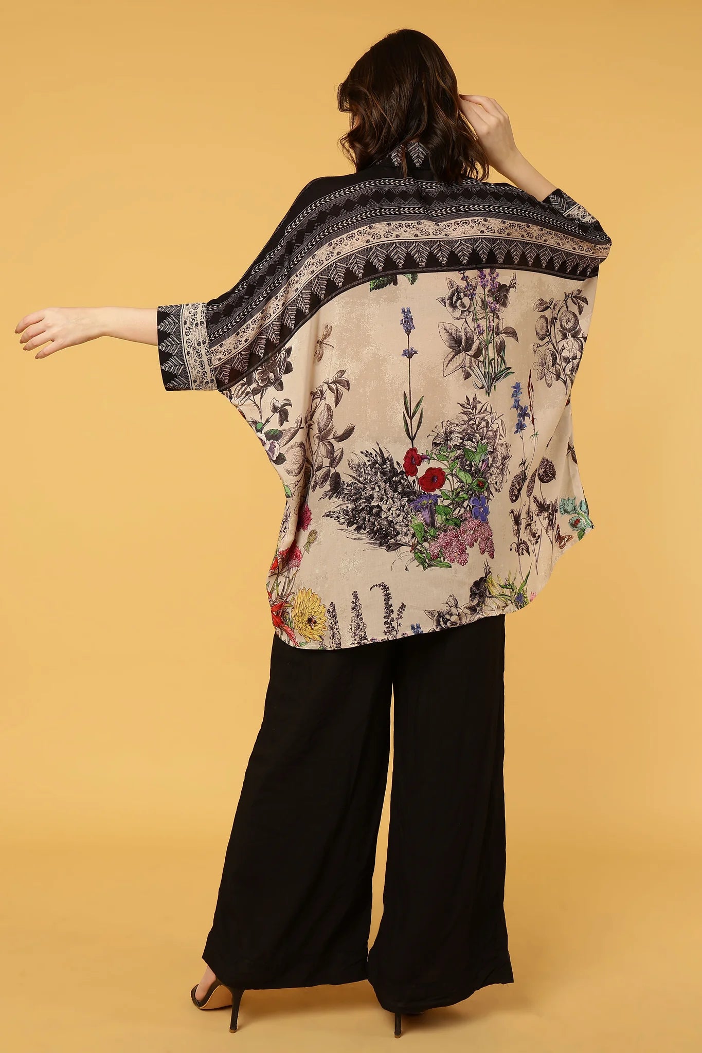 Woman wearing a floral kimono-style garment with a beige background