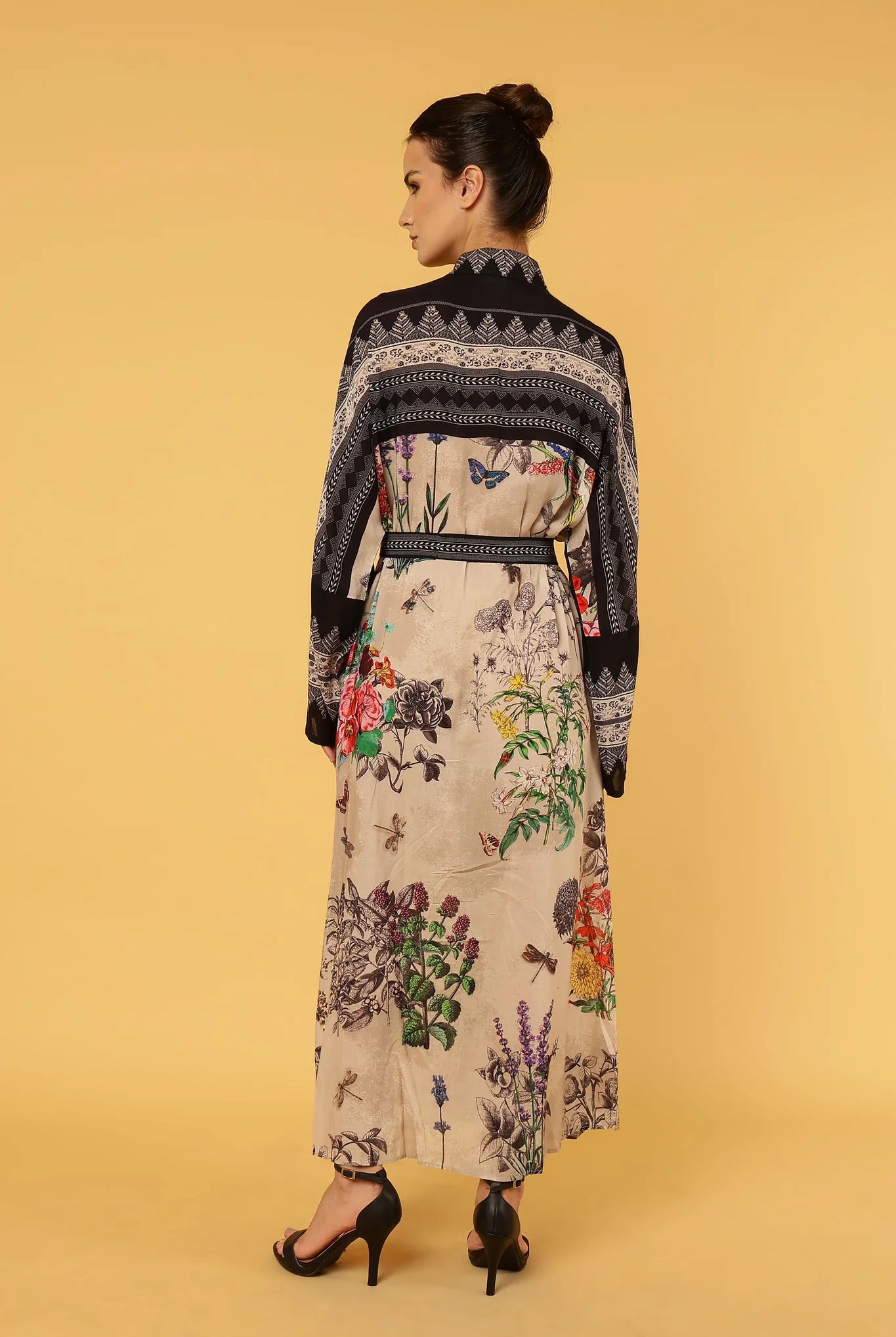 Woman wearing a floral dress with a black pattern on a yellow background