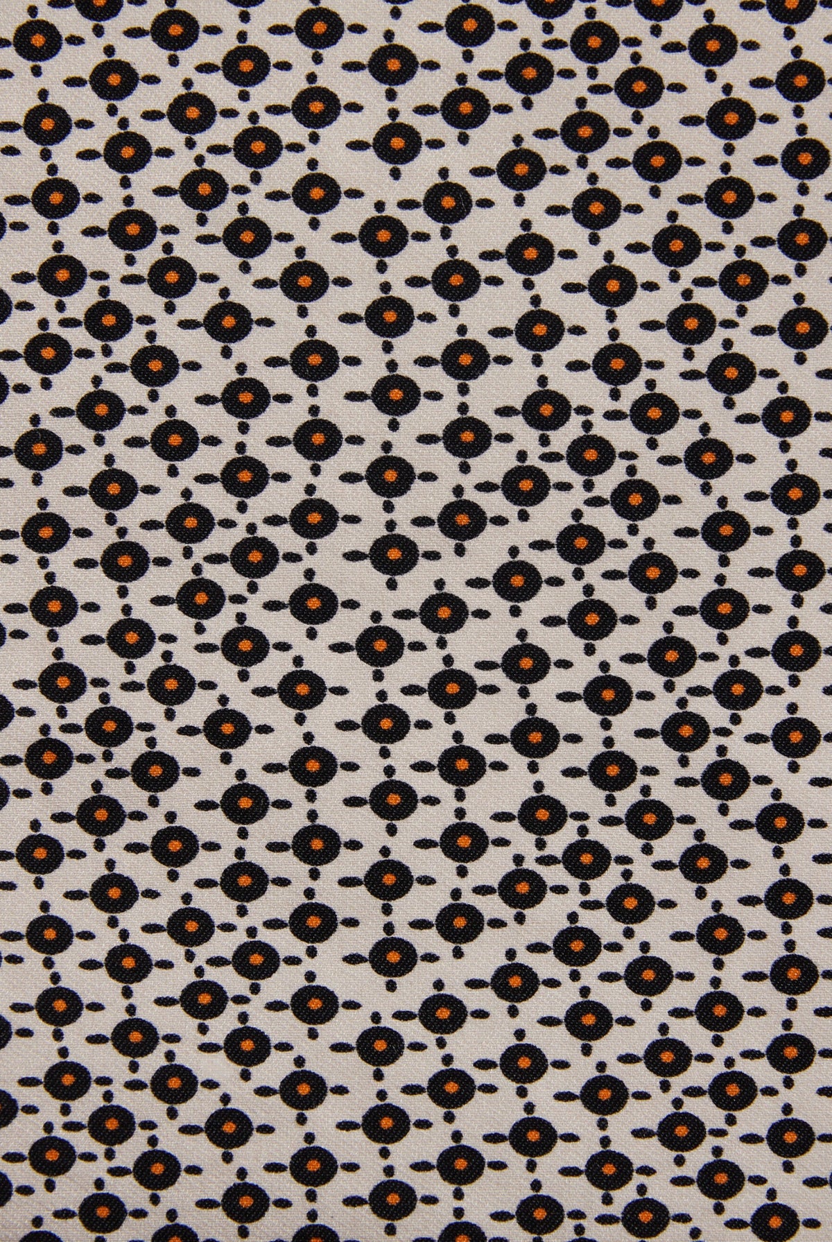 A close-up of a fabric pattern featuring a repeating geometric design of small black circles and dots on a light beige background, with some motifs highlighted in orange.