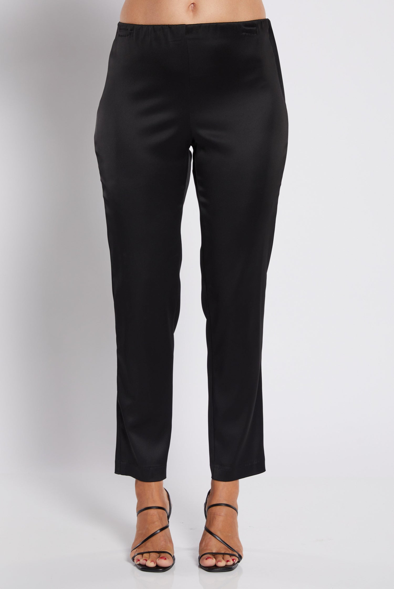 Black cropped pants shown on a model from the waist down, paired with black strappy high-heeled sandals against a light gray studio background.