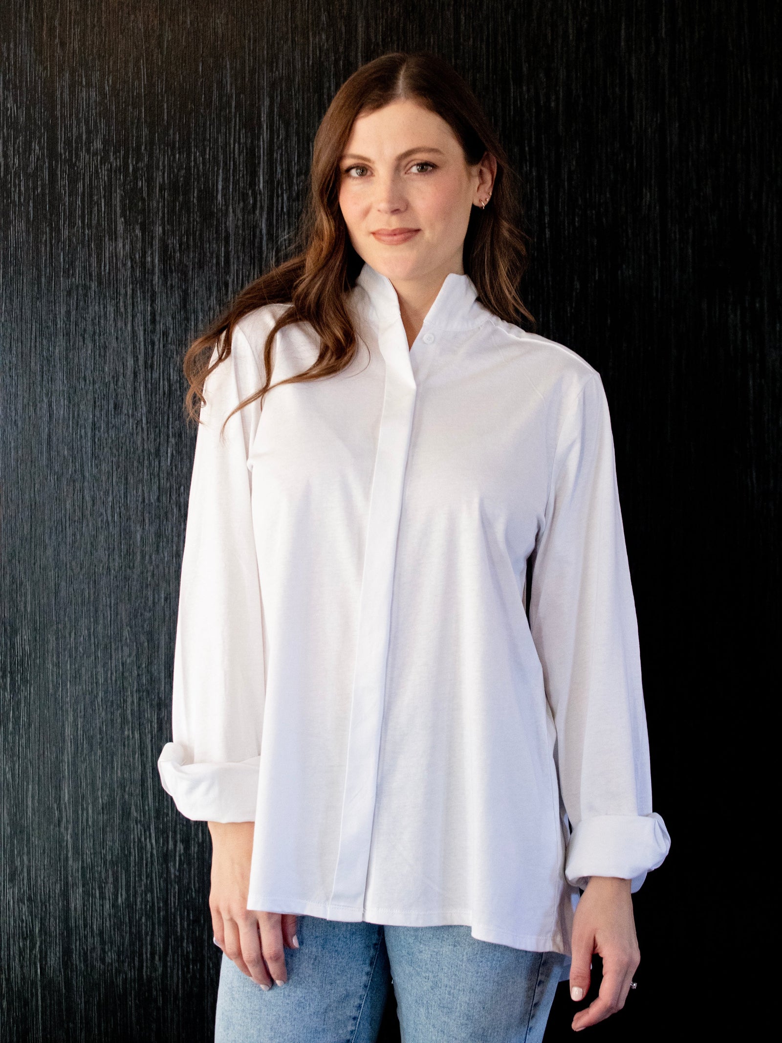 Woman wearing a white shirt against a dark background