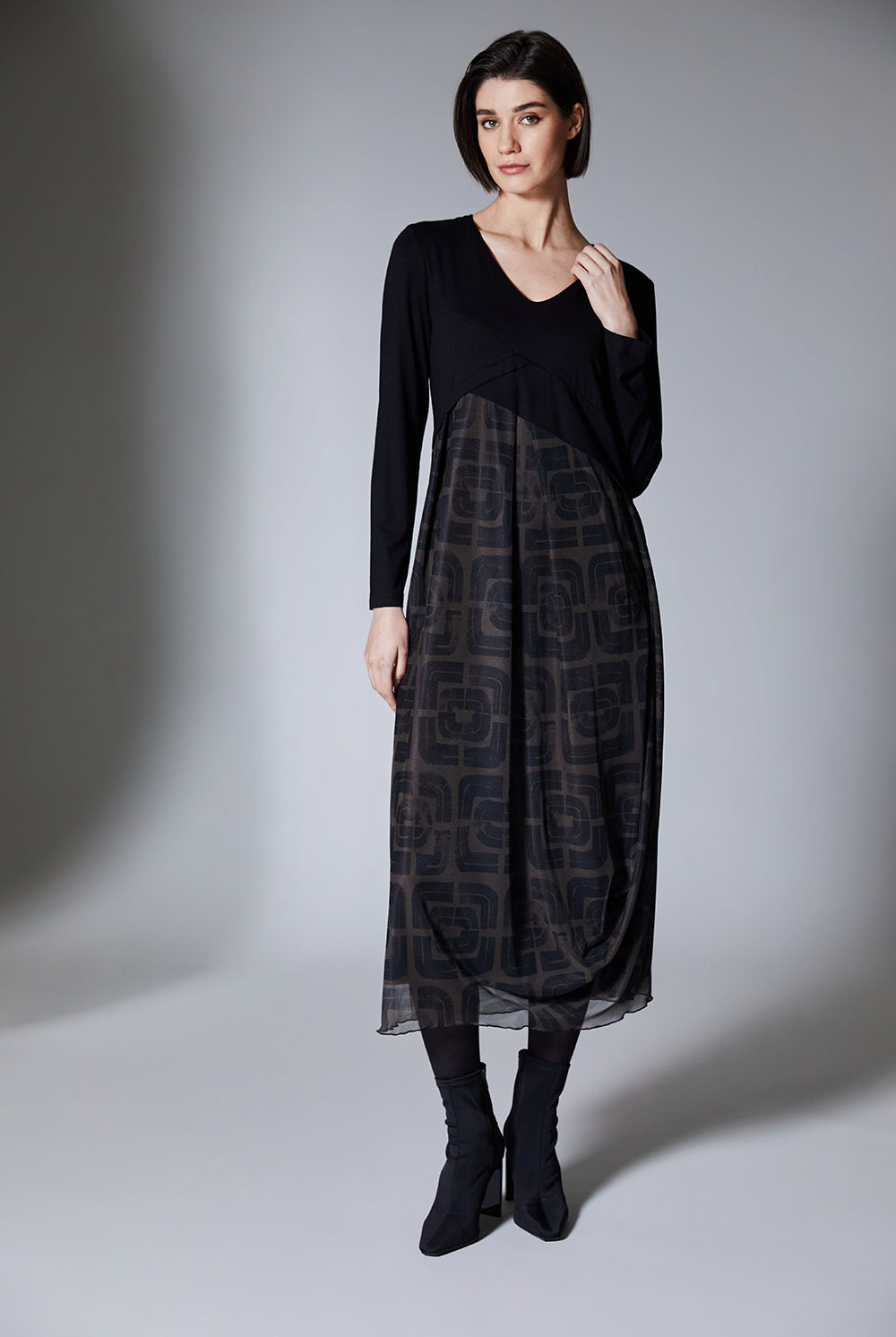 Woman wearing a black and brown patterned dress on a gray background