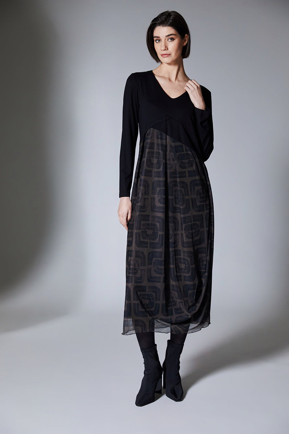 Woman wearing a black and brown patterned dress on a gray background