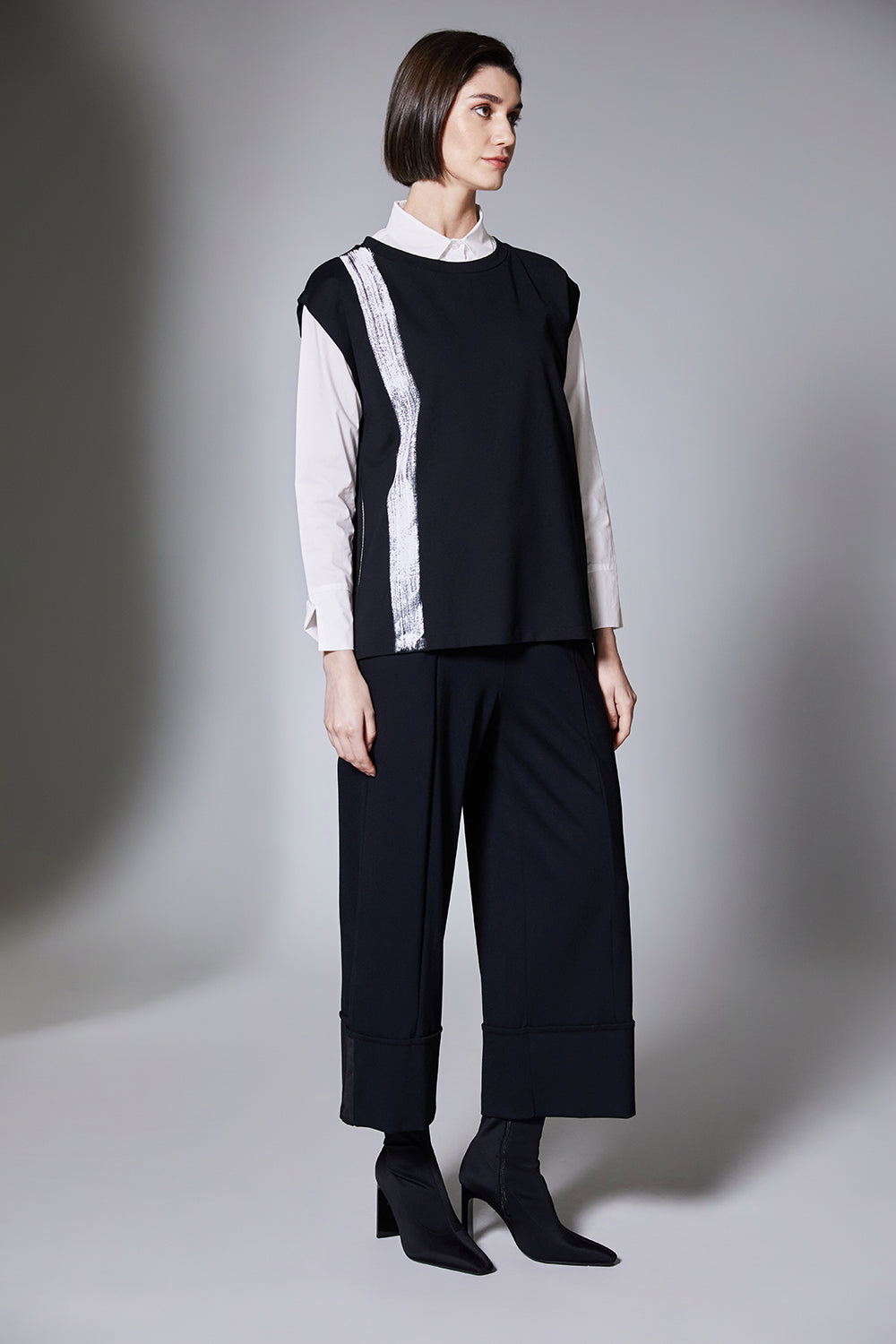 Person wearing a black and white outfit with wide-leg pants on a gray background