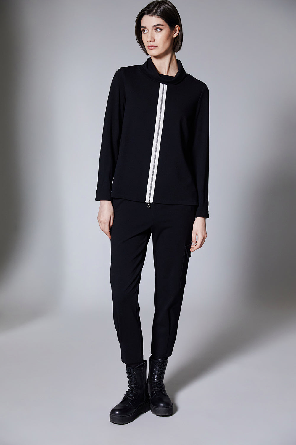 Person wearing a black outfit with a white stripe on a gray background