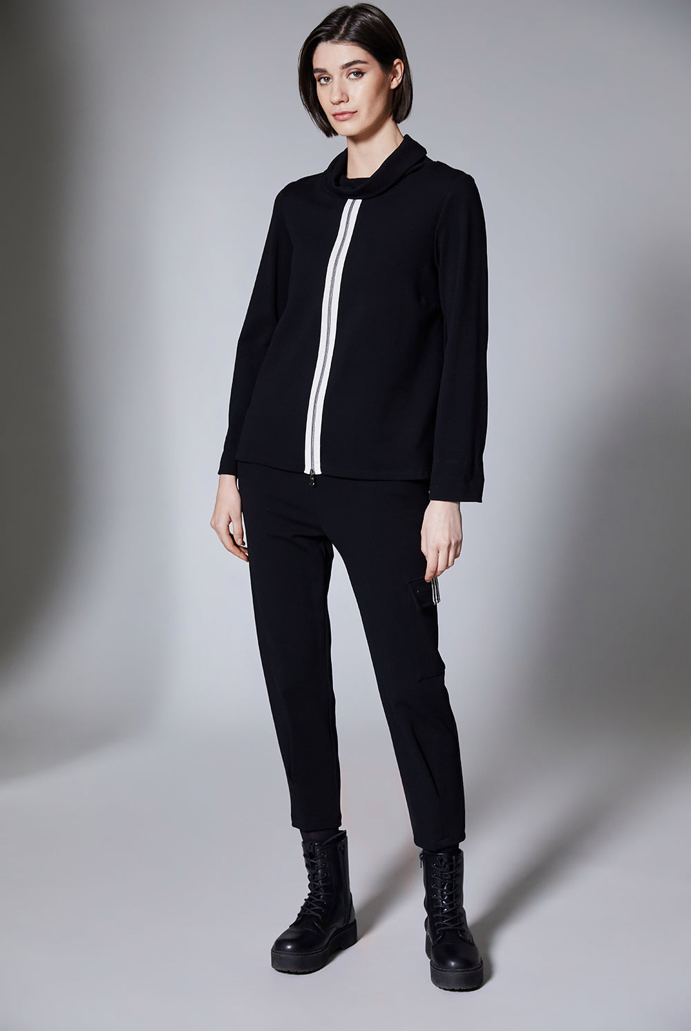 Person wearing a black outfit with a white stripe on a gray background