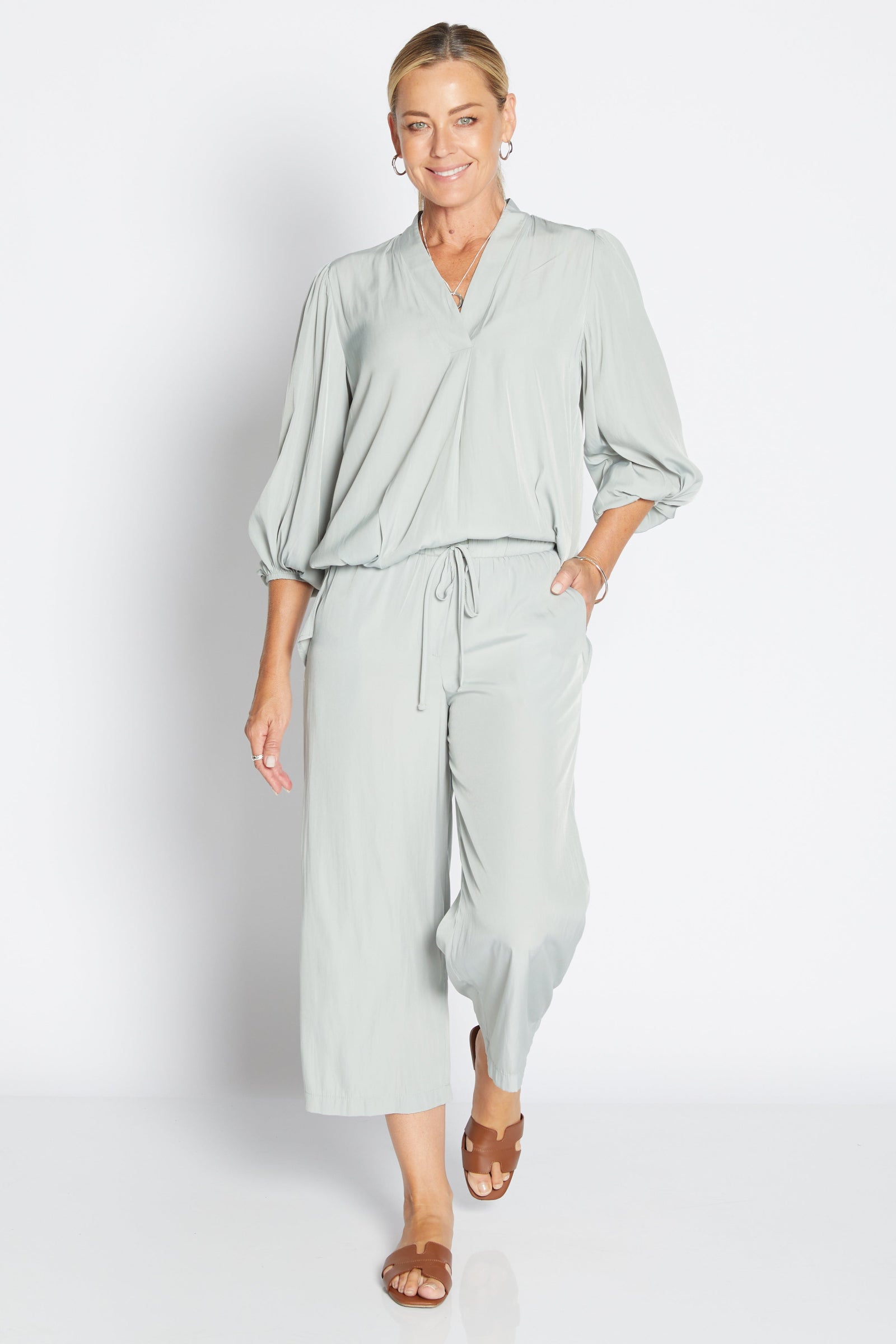 Woman wearing a sage green outfit on a white background