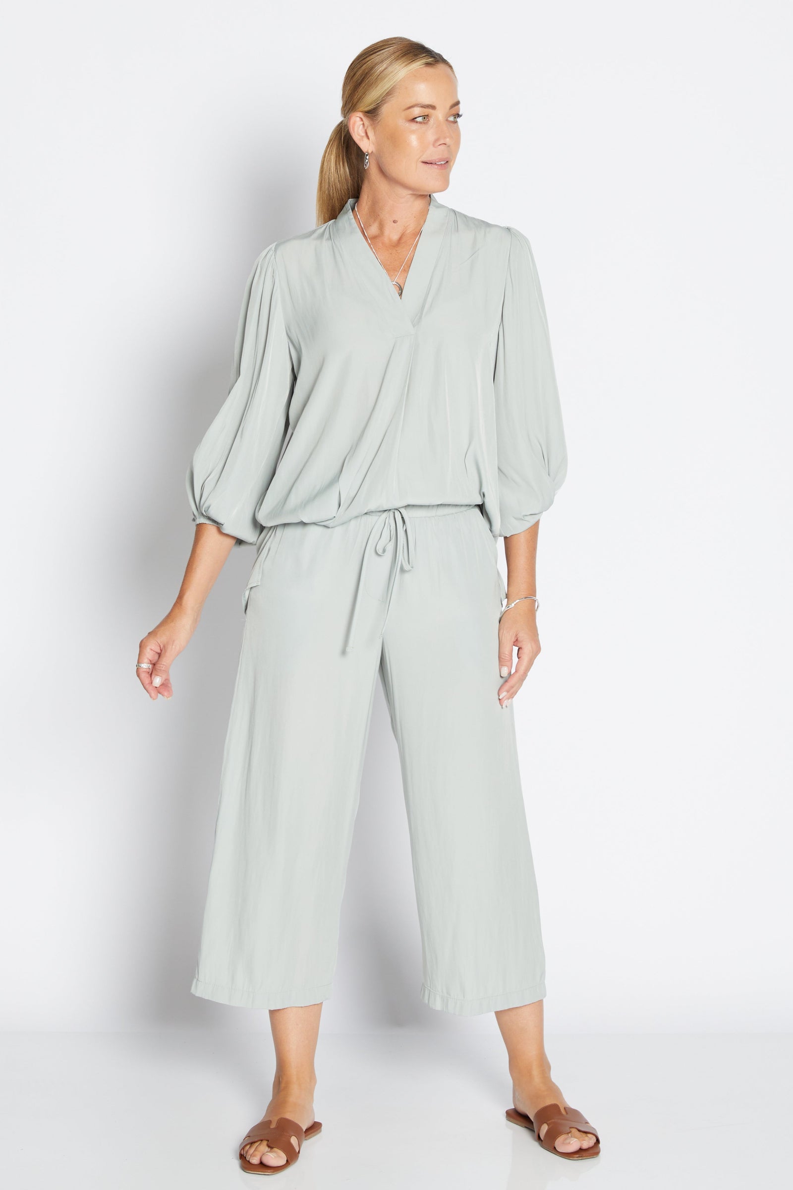 Woman wearing a sage green two piece set on a white background