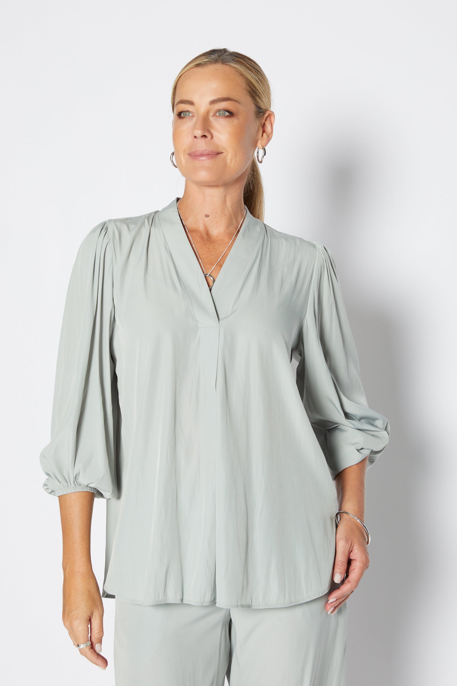 Woman wearing a light green blouse against a plain background