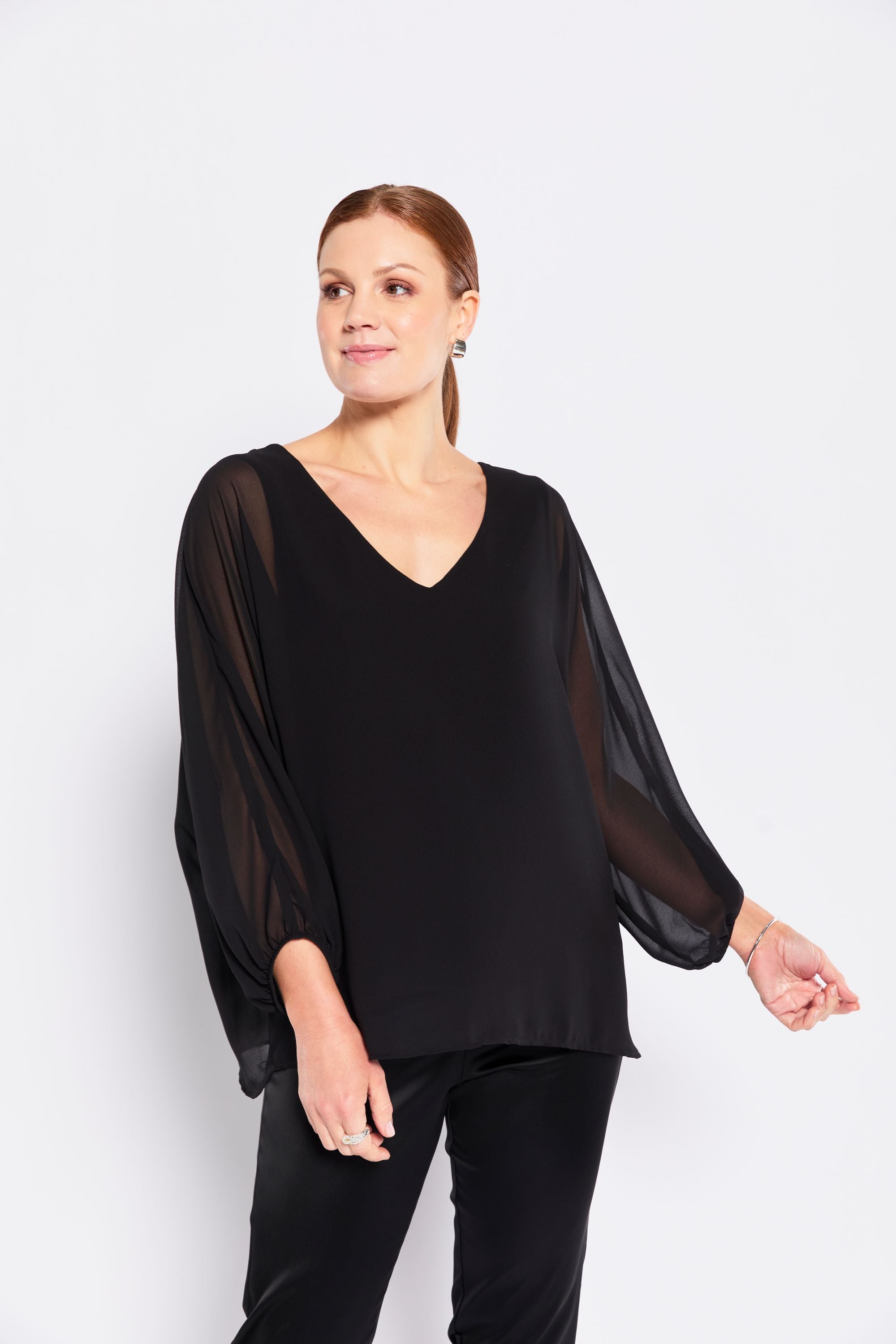 Woman wearing a black blouse with sheer sleeves on a white background