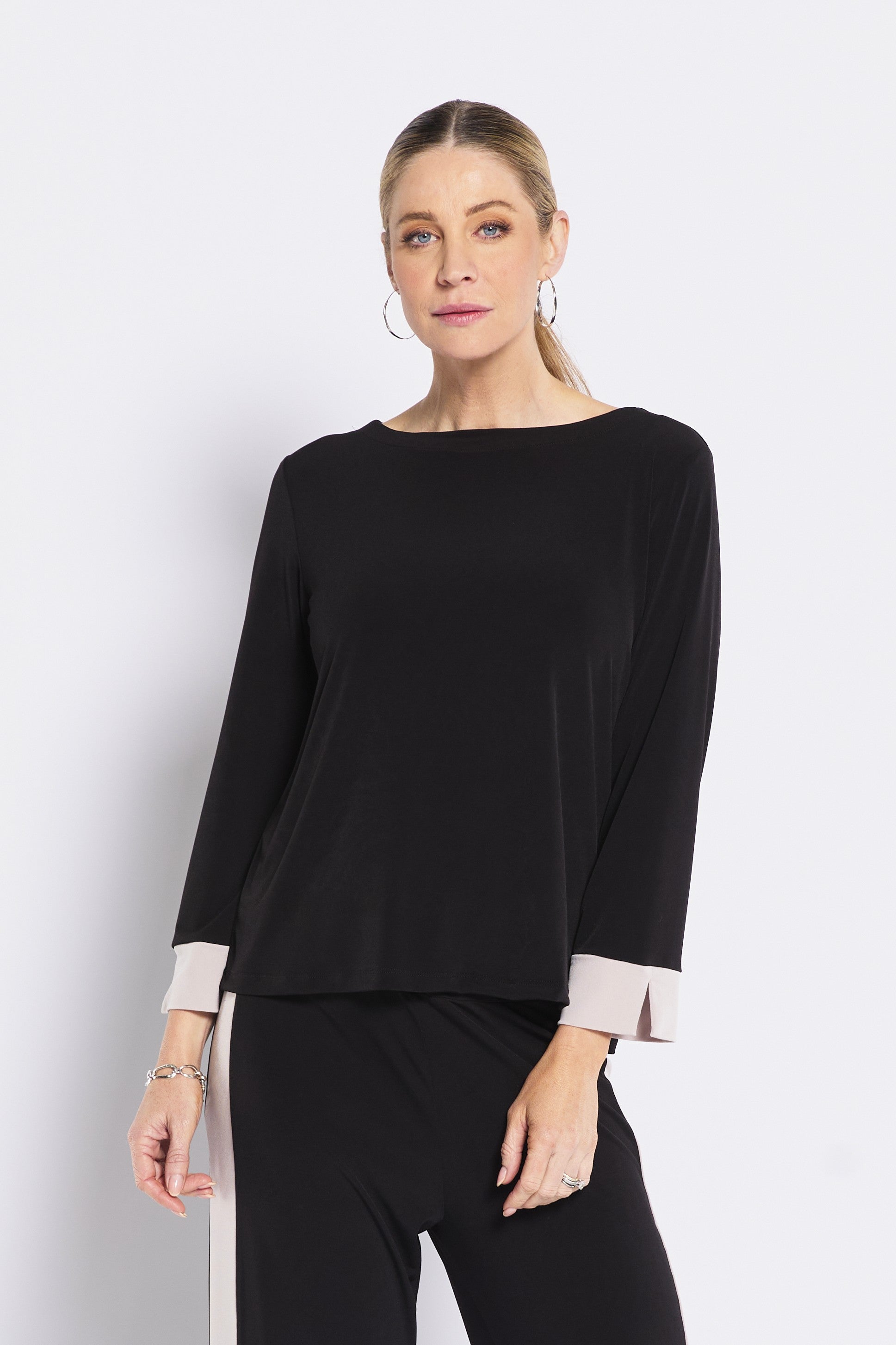 Woman wearing a black top with beige cuffs on a white background