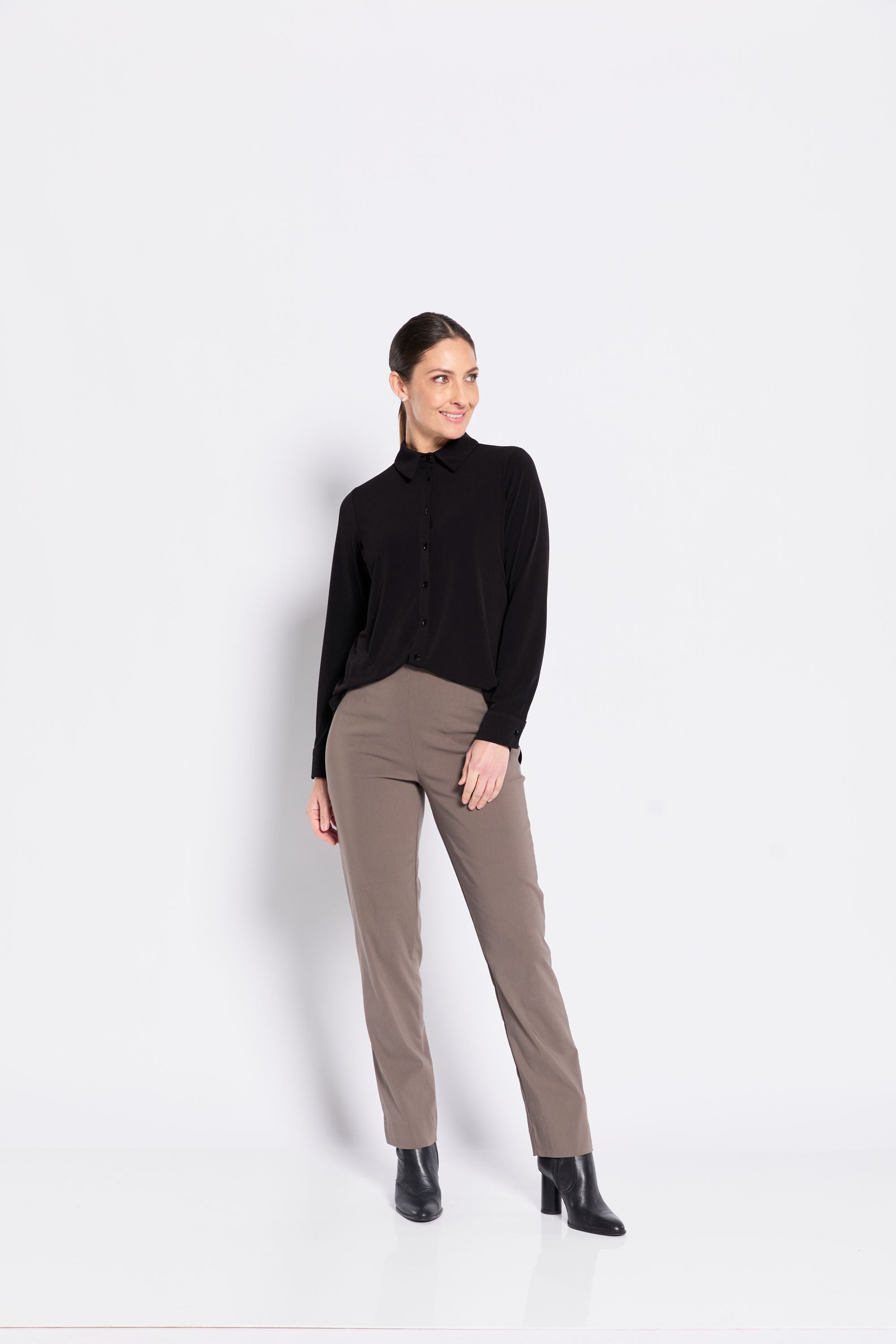 Woman wearing a black shirt and beige pants on a white background