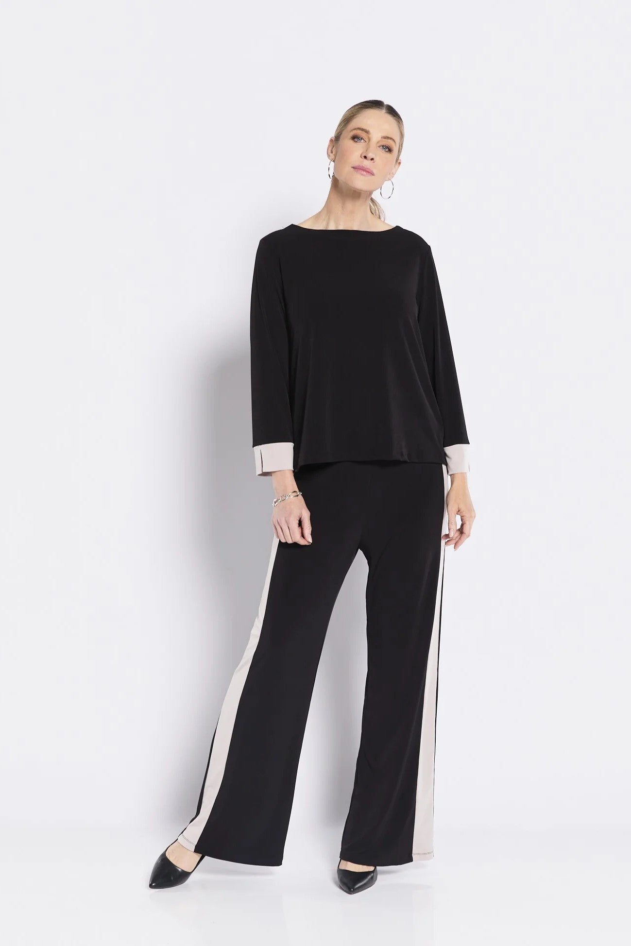 Woman wearing a black outfit with white trim on a white background