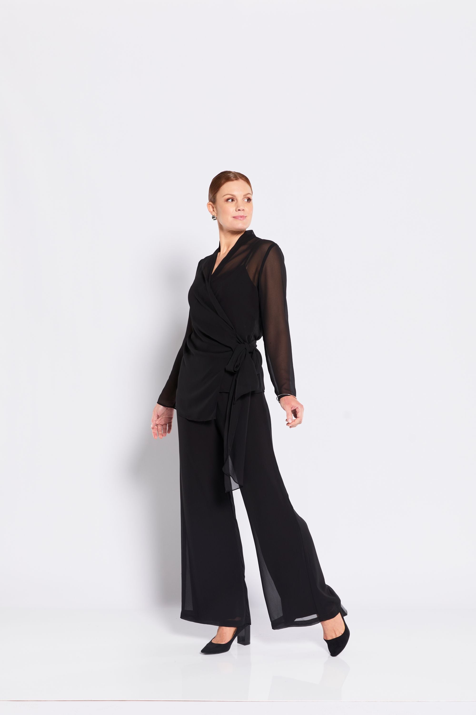 Woman wearing a black outfit with sheer sleeves on a white background