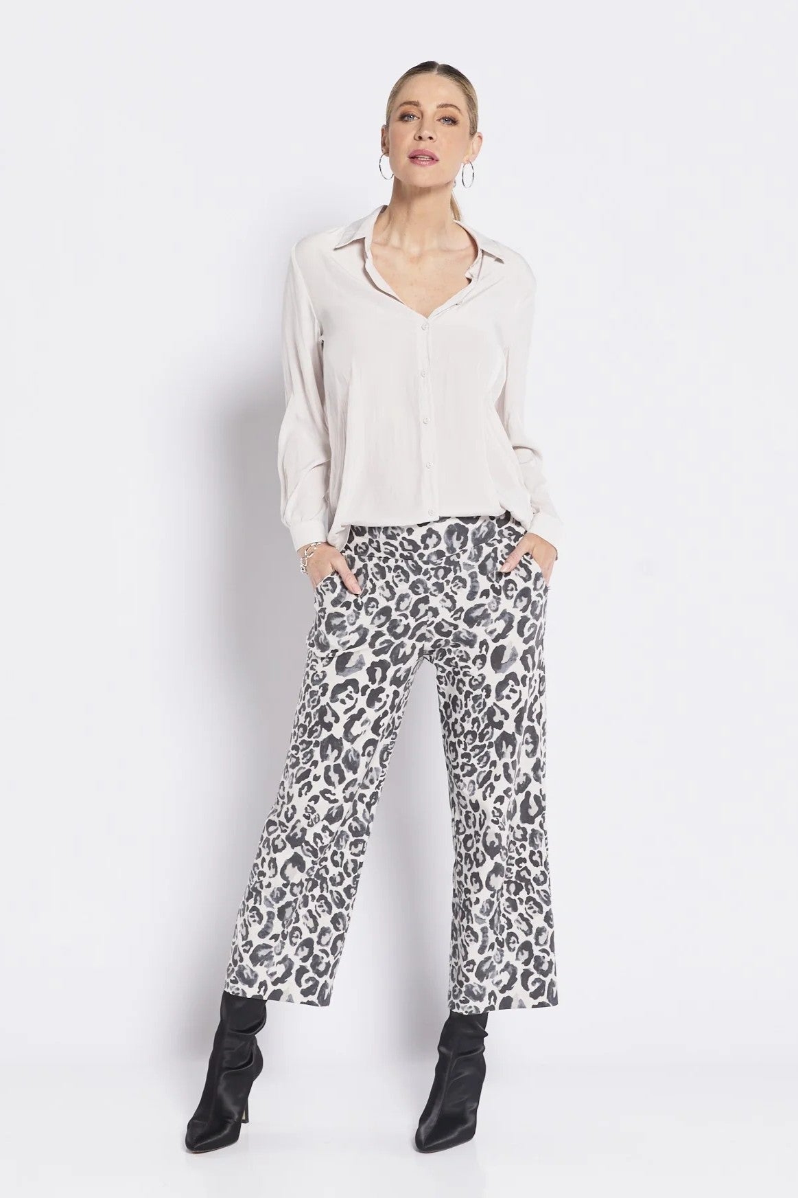 Woman wearing a white blouse and leopard print pants on a white background