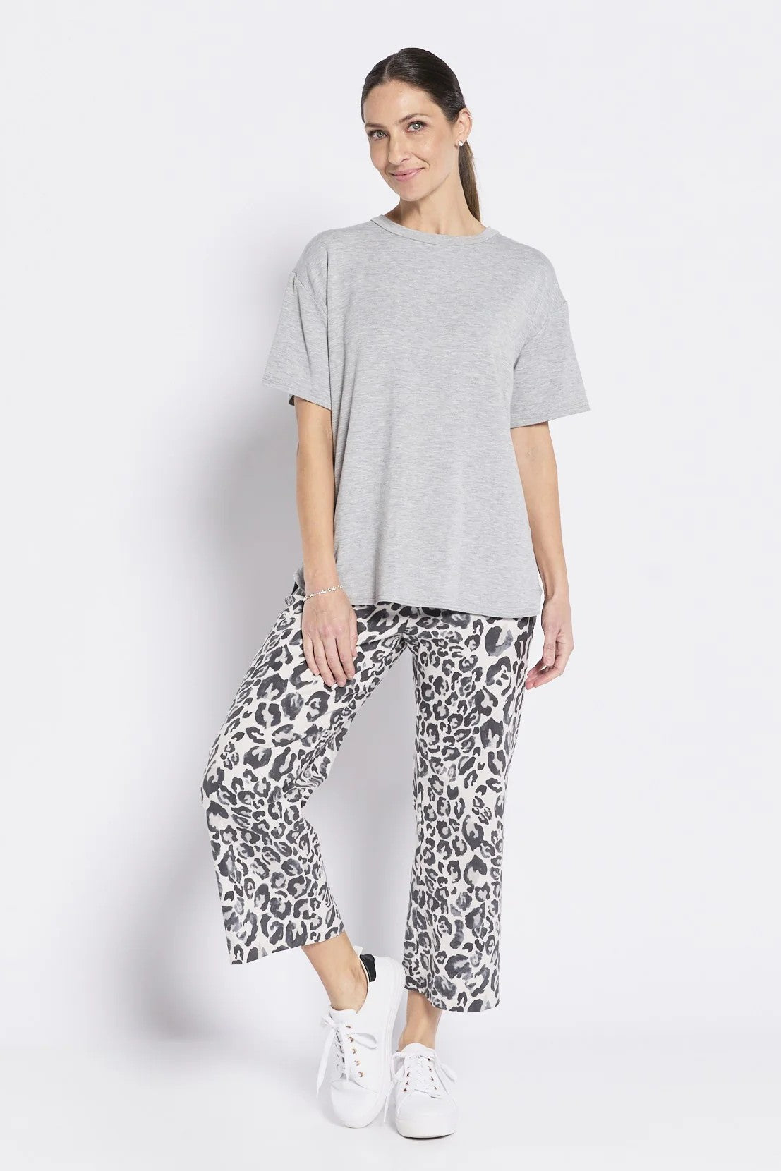 Woman wearing a gray t-shirt and leopard print pants on a white background
