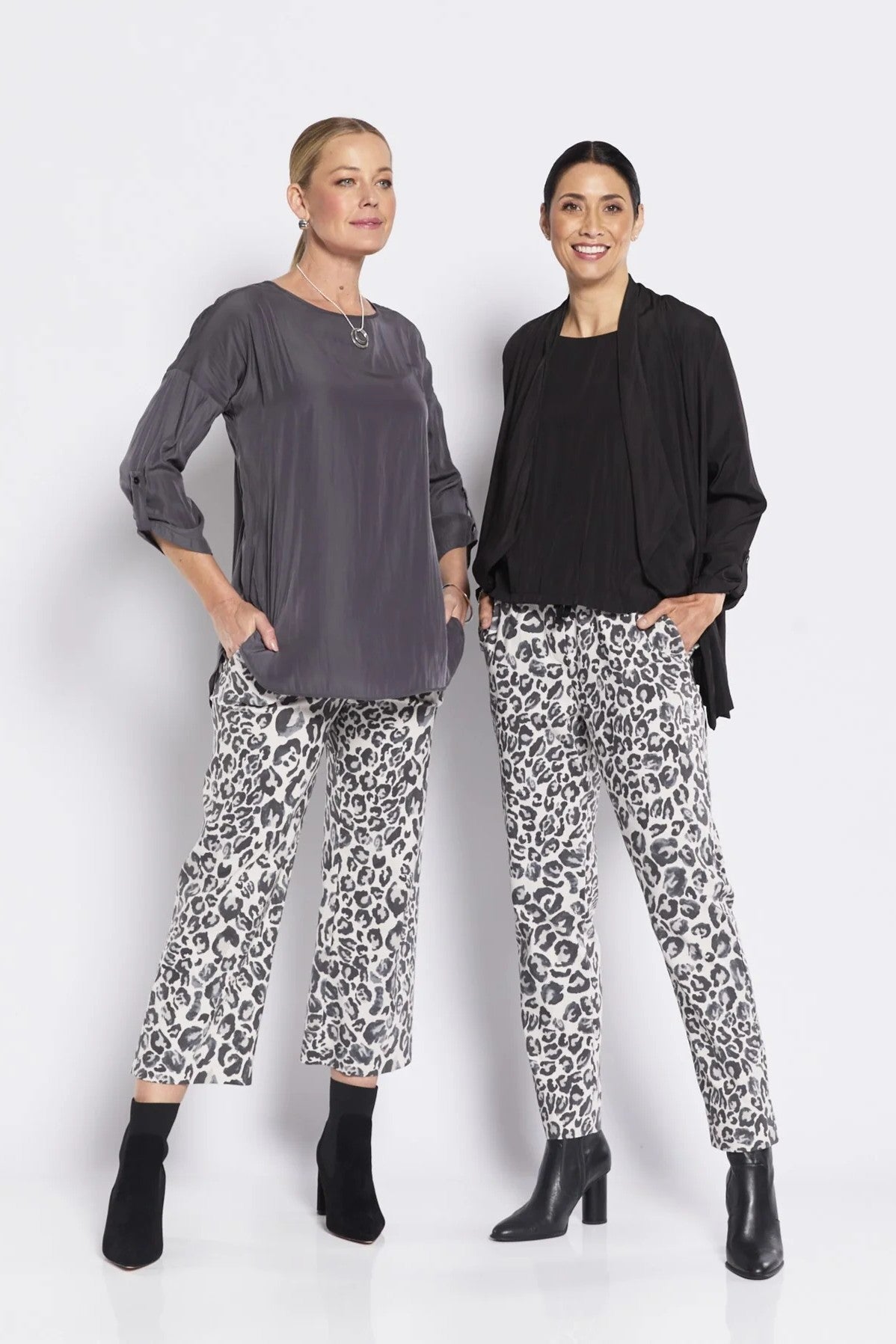 Two women wearing matching outfits with leopard print pants on a white background