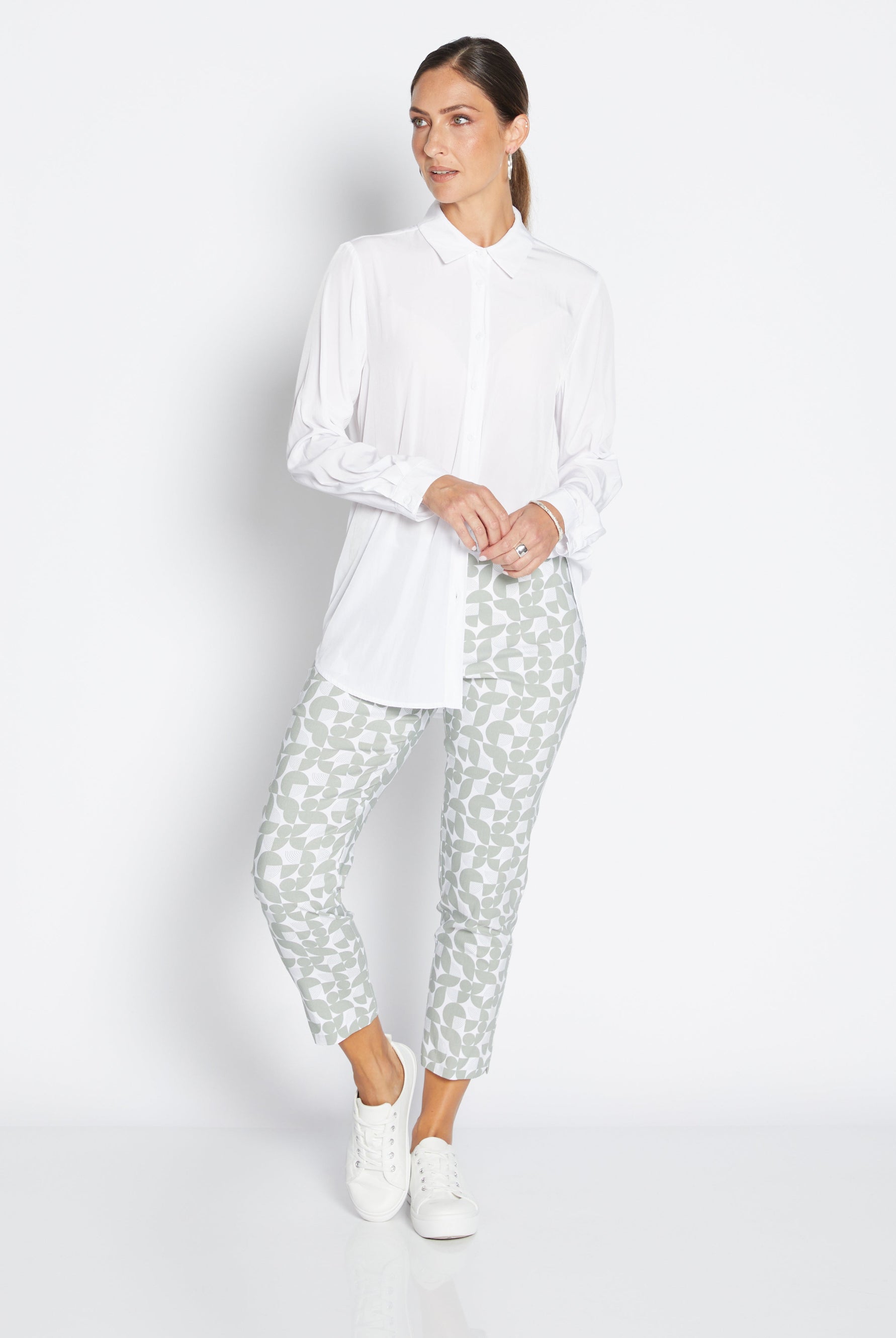 Woman wearing a white shirt and patterned pants on a white background