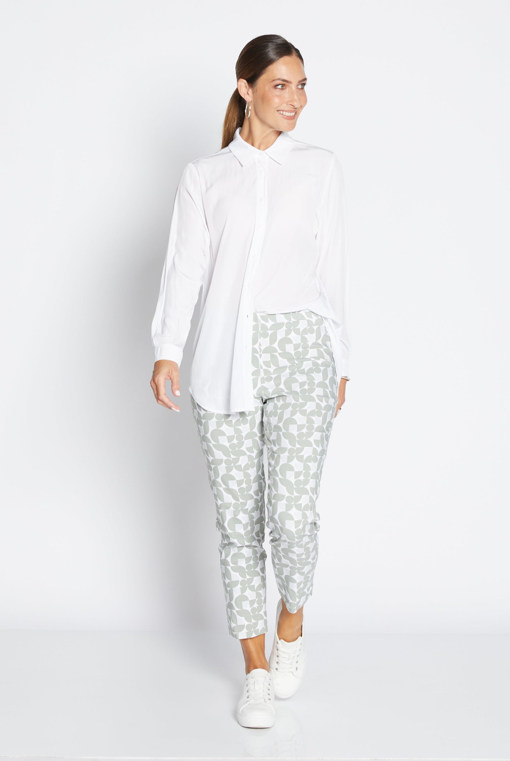 Woman wearing a white blouse and patterned pants on a white background