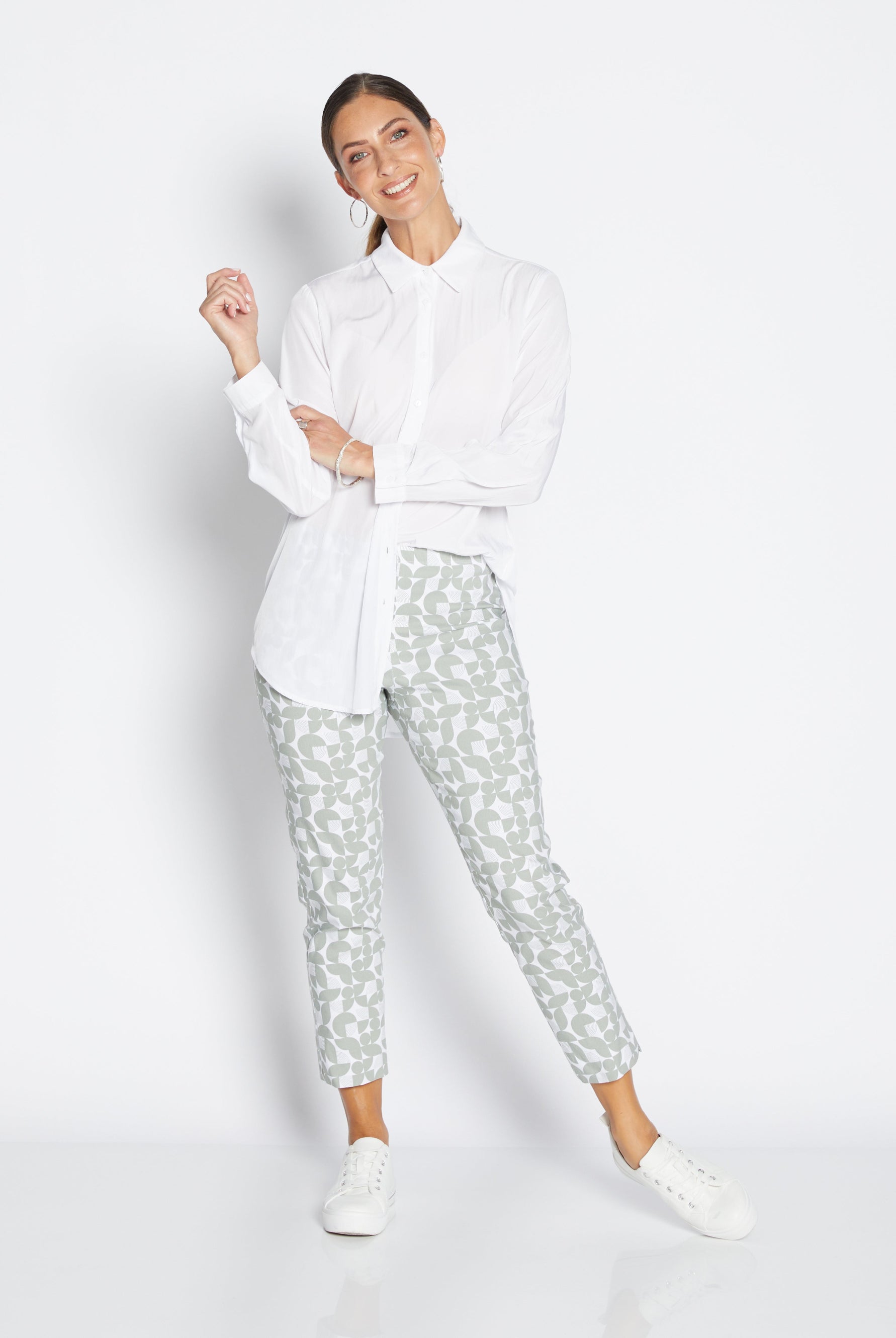 Woman wearing a white shirt and patterned pants on a white background