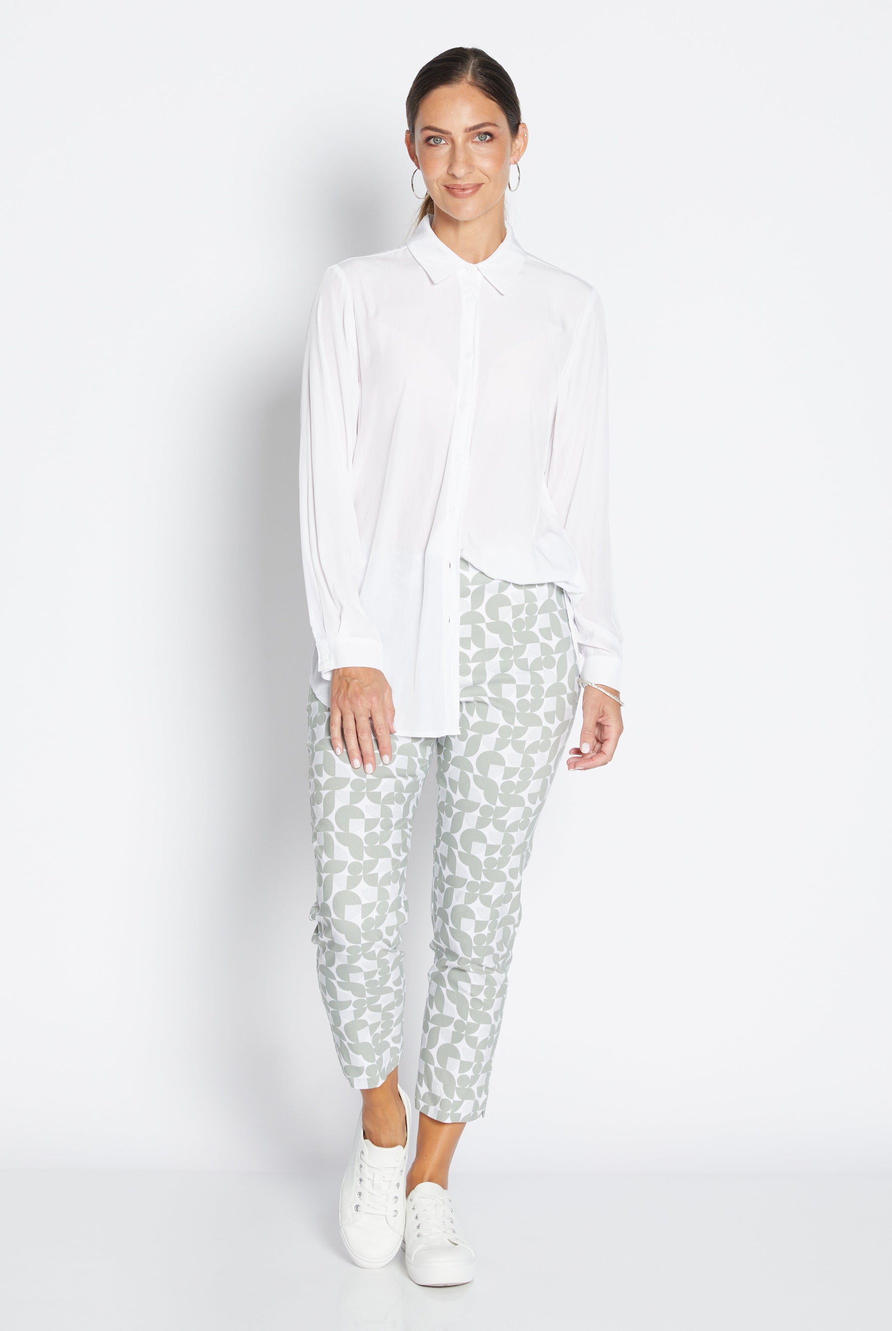 Woman wearing a white shirt and patterned pants on a white background