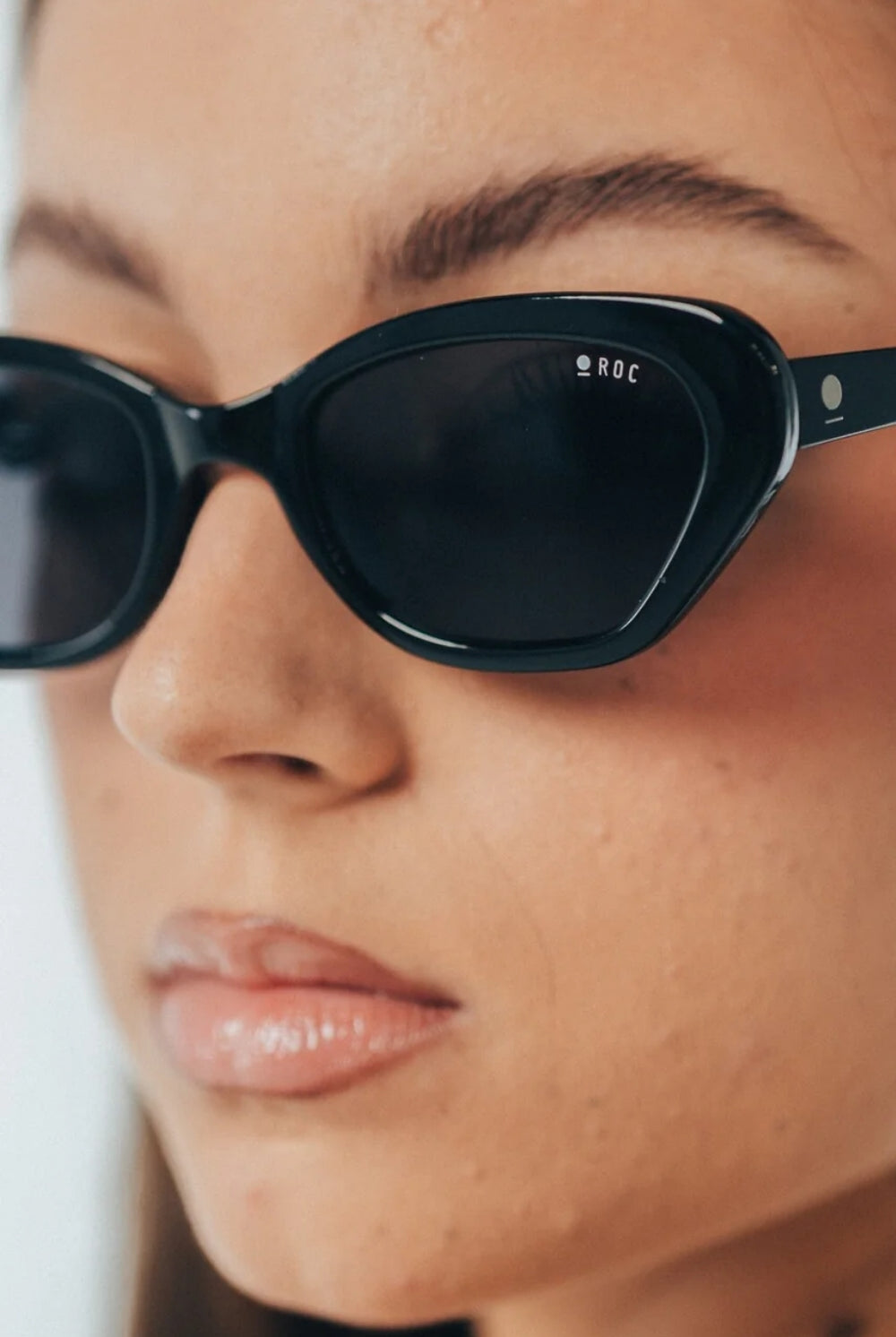 Close-up of a person wearing black sunglasses with 'ROC' branding.