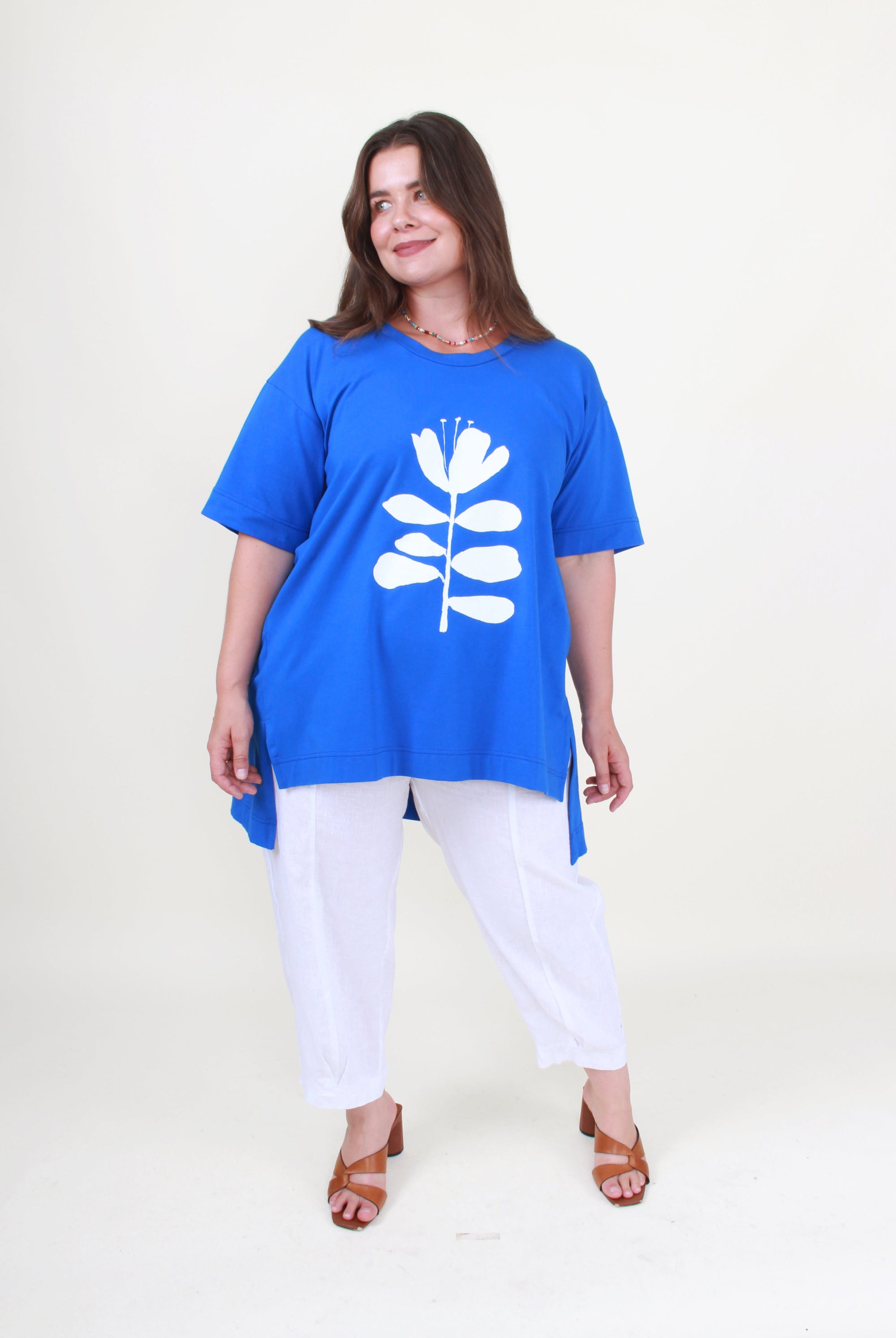 Woman wearing a blue tunic with a white floral design on a plain background