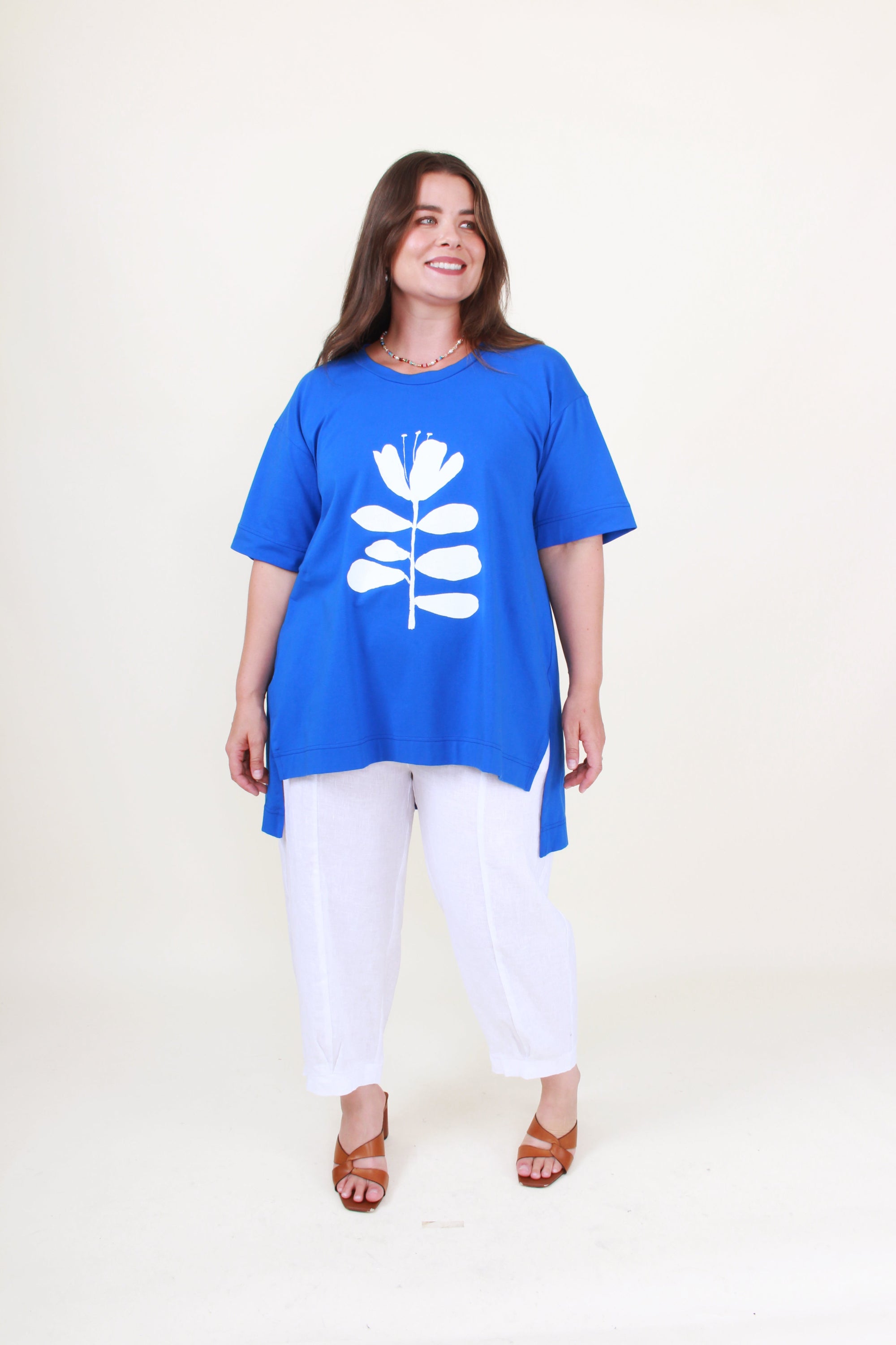 Woman wearing a blue tunic with a white floral design on a plain background