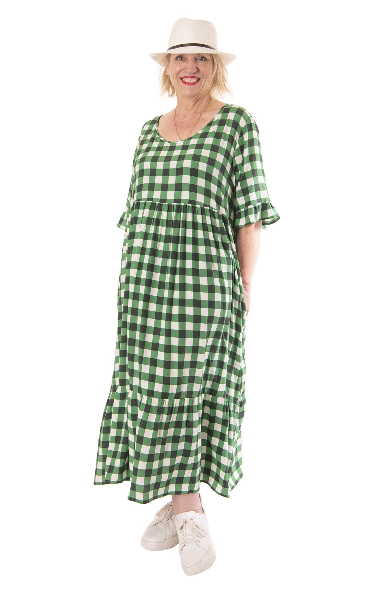 Woman wearing a green checkered dress and white hat on a white background